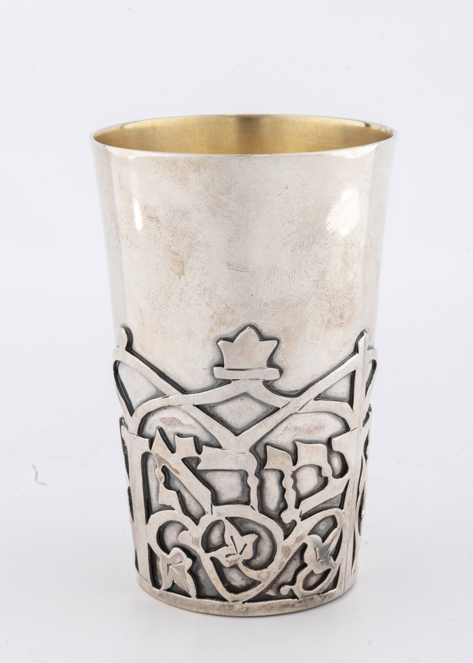 A HAND WROUGHT KIDDUSH CUP BY DOVID COHEN. Jerusalem, modern.: Beaker form. With lattice work overlay spelling out BORAY PRI HAGAFEN