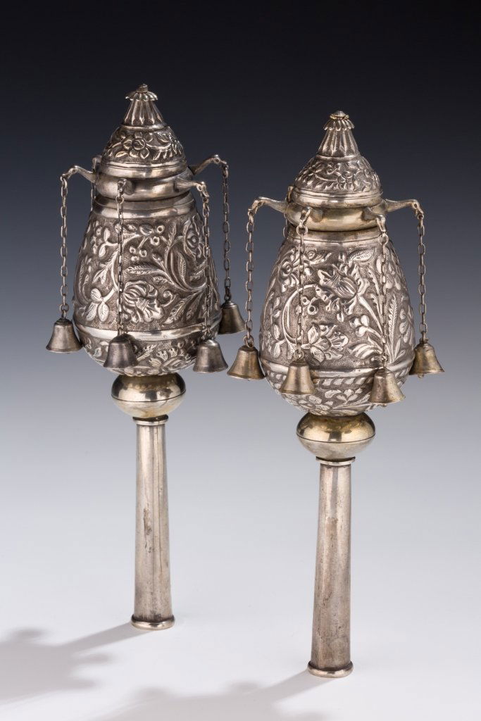 A Pair of Silver Torah Finials: A Pair of Silver Torah Finials. Persia, 19th century. The upper portion chased with floral patterns and hung with bells suspended from long chains forming a canopy of chains and bells, all on narrow s