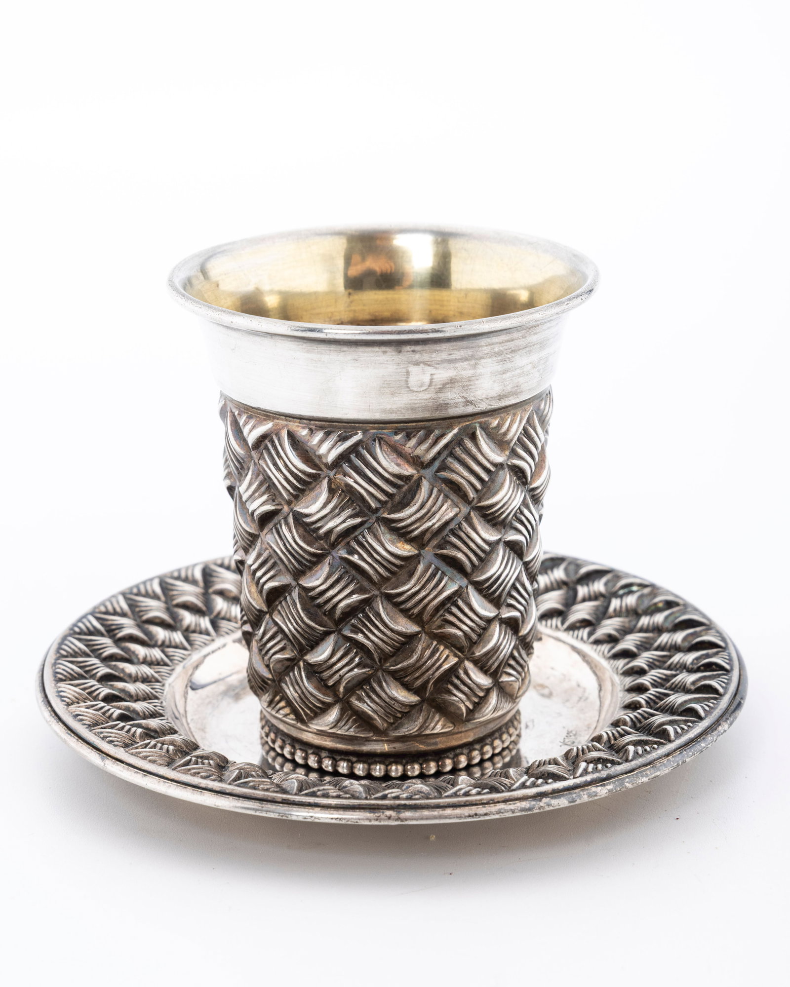 A STERLING SILVER KIDDUSH CUP AND PLATE: Israel, c. 2000. In a basket weave design. The cup is 3.5" tall and the plate is 4.5" wide. Total weight is 135 grams.