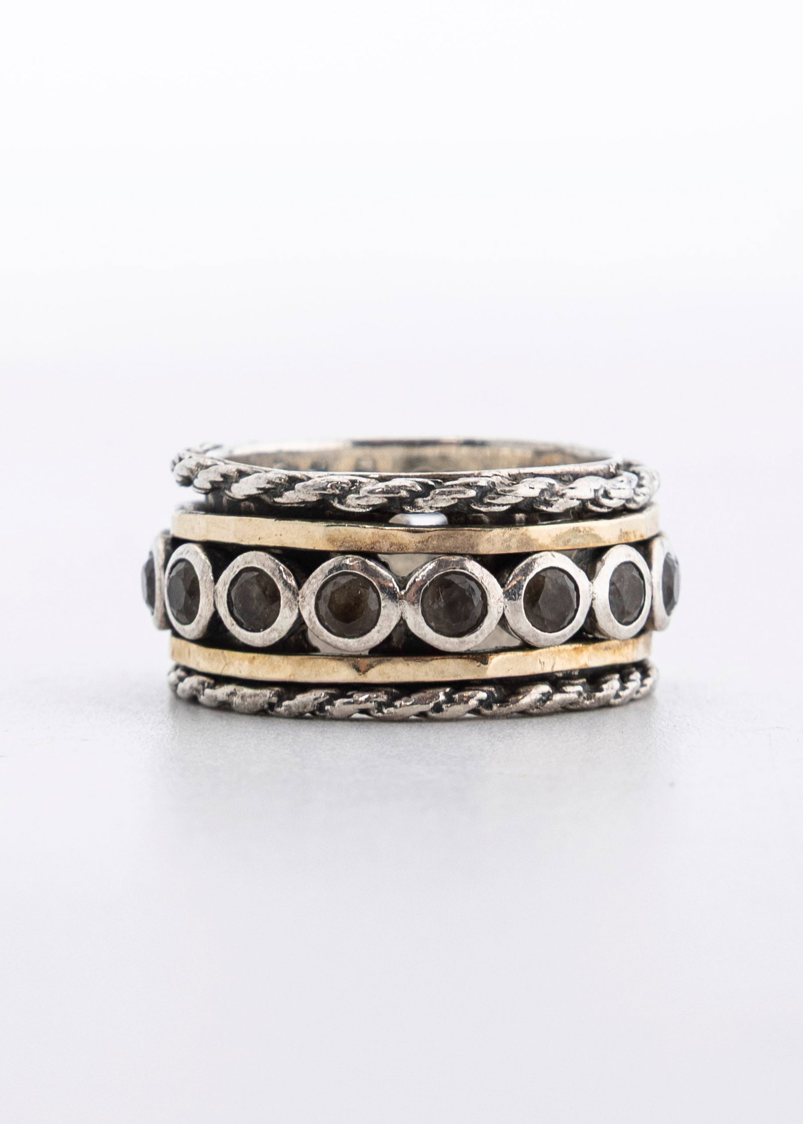 A 14K AND STERLING SILVER RING. Israel, modern: The base is sterling silver with two 14K bands on top and bottom of fitted amethyst stones. Total weight is 9.8 grams