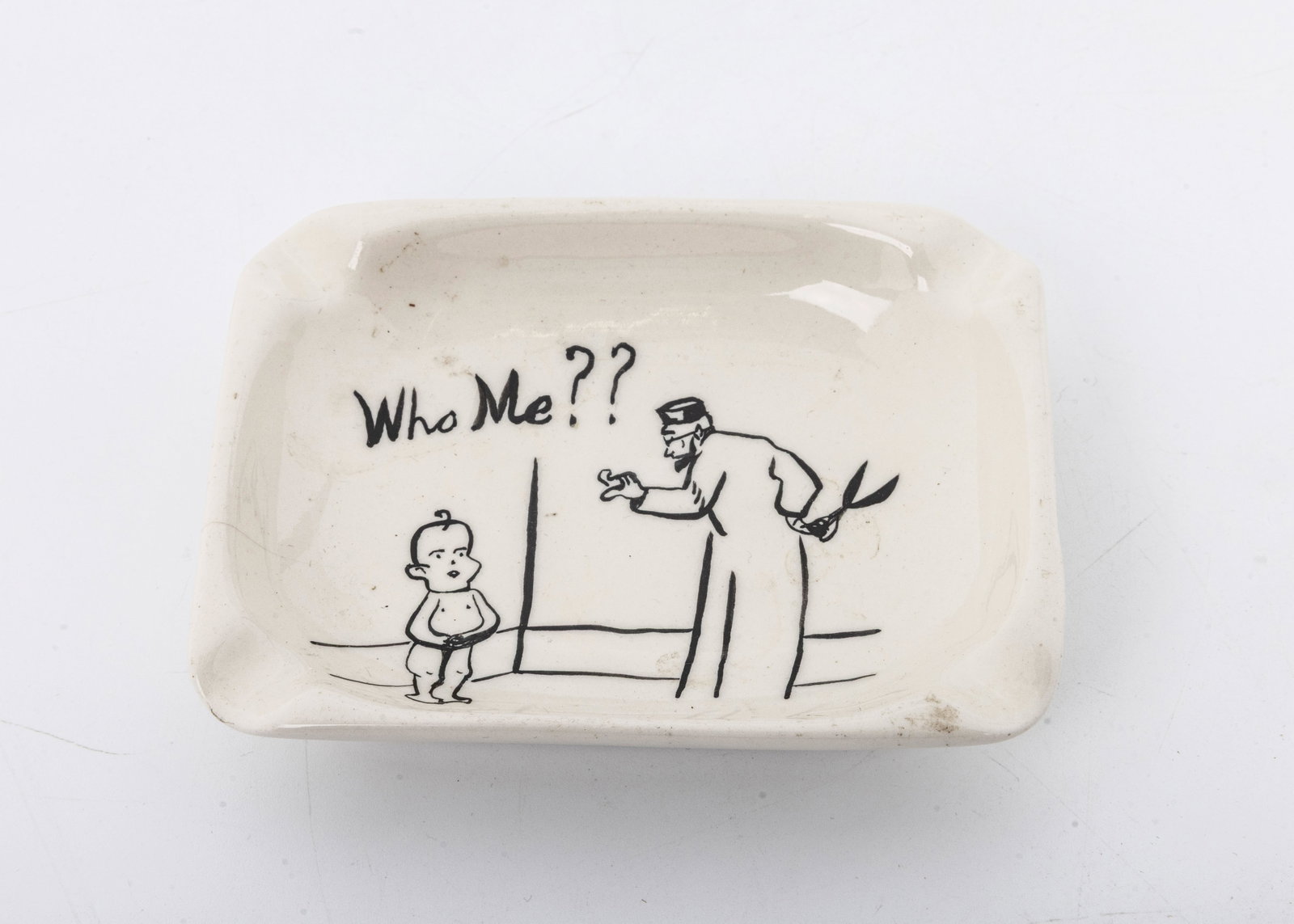AN ANTI-SEMITIC ASH TRAY BY BONSACK, 1953: Depicting an Orthodox looking mohel with a scissor and a baby covering his private area stating WHO ME? Chipped along the bottom rim. 4.6" x 3.7"