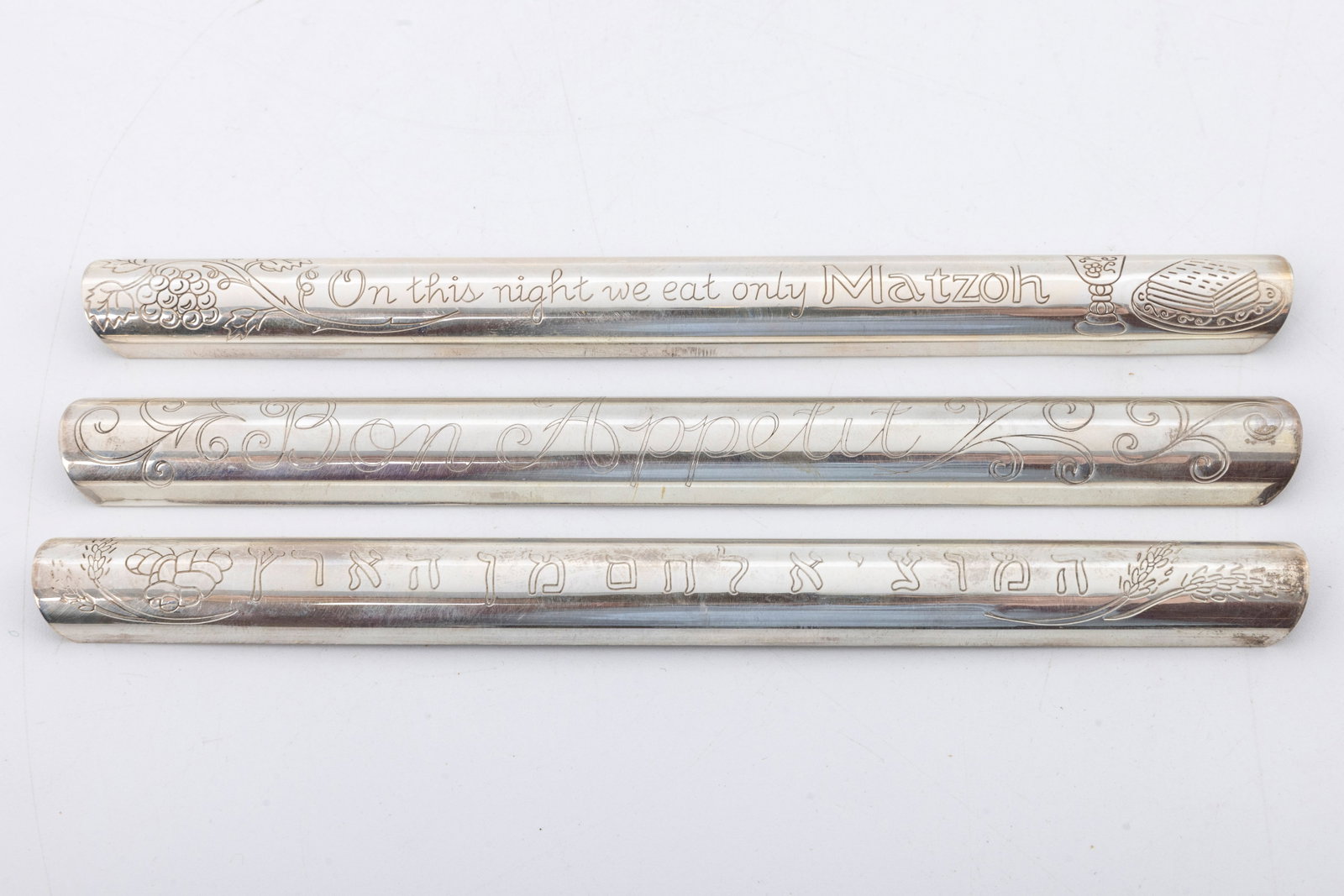 THREE STERLING SILVER JUDAIC CRUMB SWEEPERS.: Each engraved with a different Hebrew bread related saying. 6.5" long and 48 grams