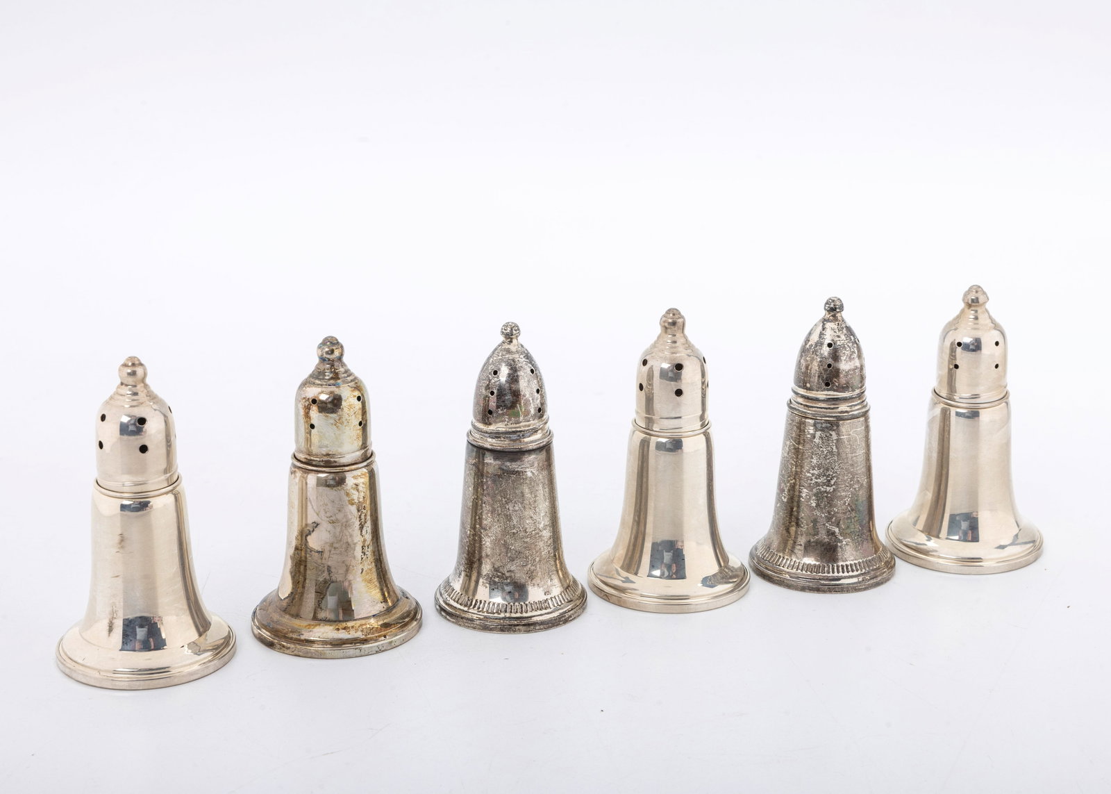A GROUP OF 6 STERLING SILVER SALT AND PEPPER SHAKERS: Each is in a bell form. Silver overlay over glass. The bottoms are makrked Sterling and Weighted. 3" tall each