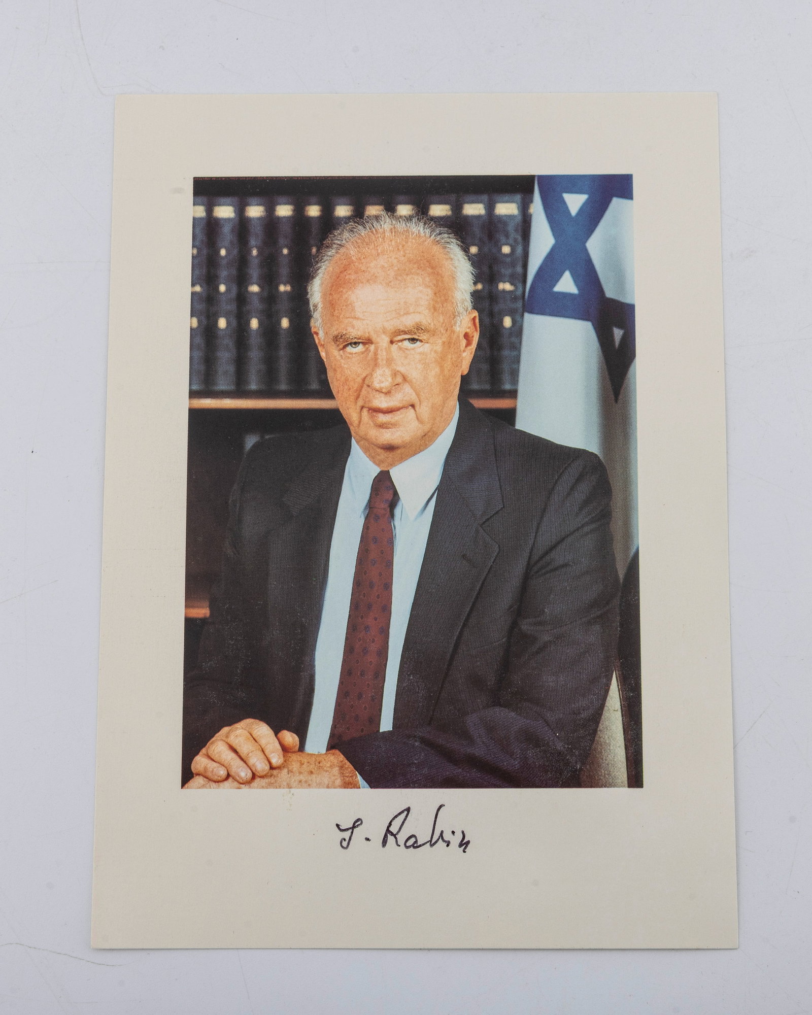AN AUTOGRAPHED PHOTO OF YITZCHAK RABIN. Israel, c. 1990.: In an official pose while standing in front of an Israel flag.