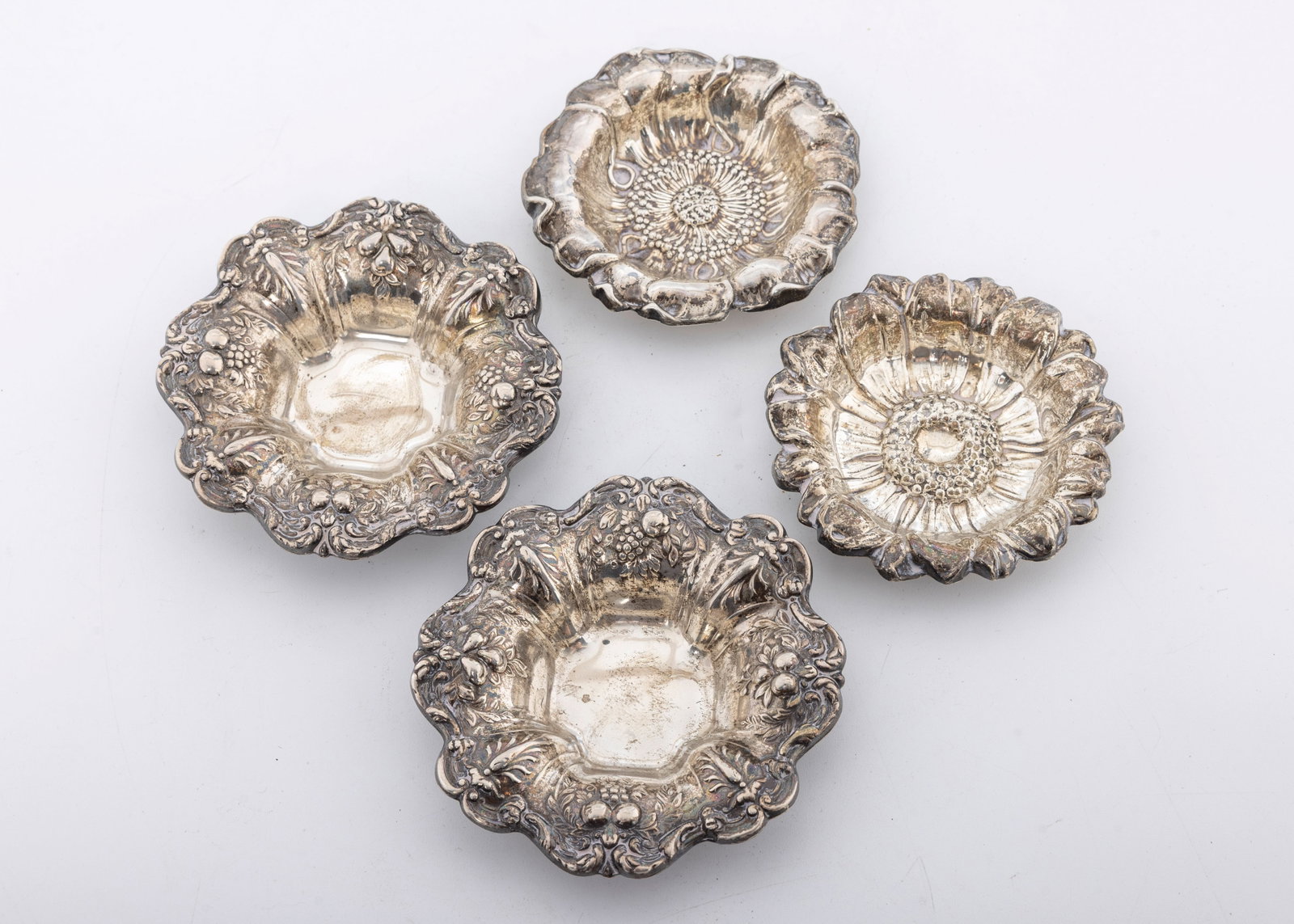 A GROUP OF FOUR STERLING SILVER SMALL BOWLS/BUTTER PATS: The first two are Reed and Barton Francis the First (3.7" wide) and the second set is by Gorham in a floral pattern (3"). Total weight is 149 grams