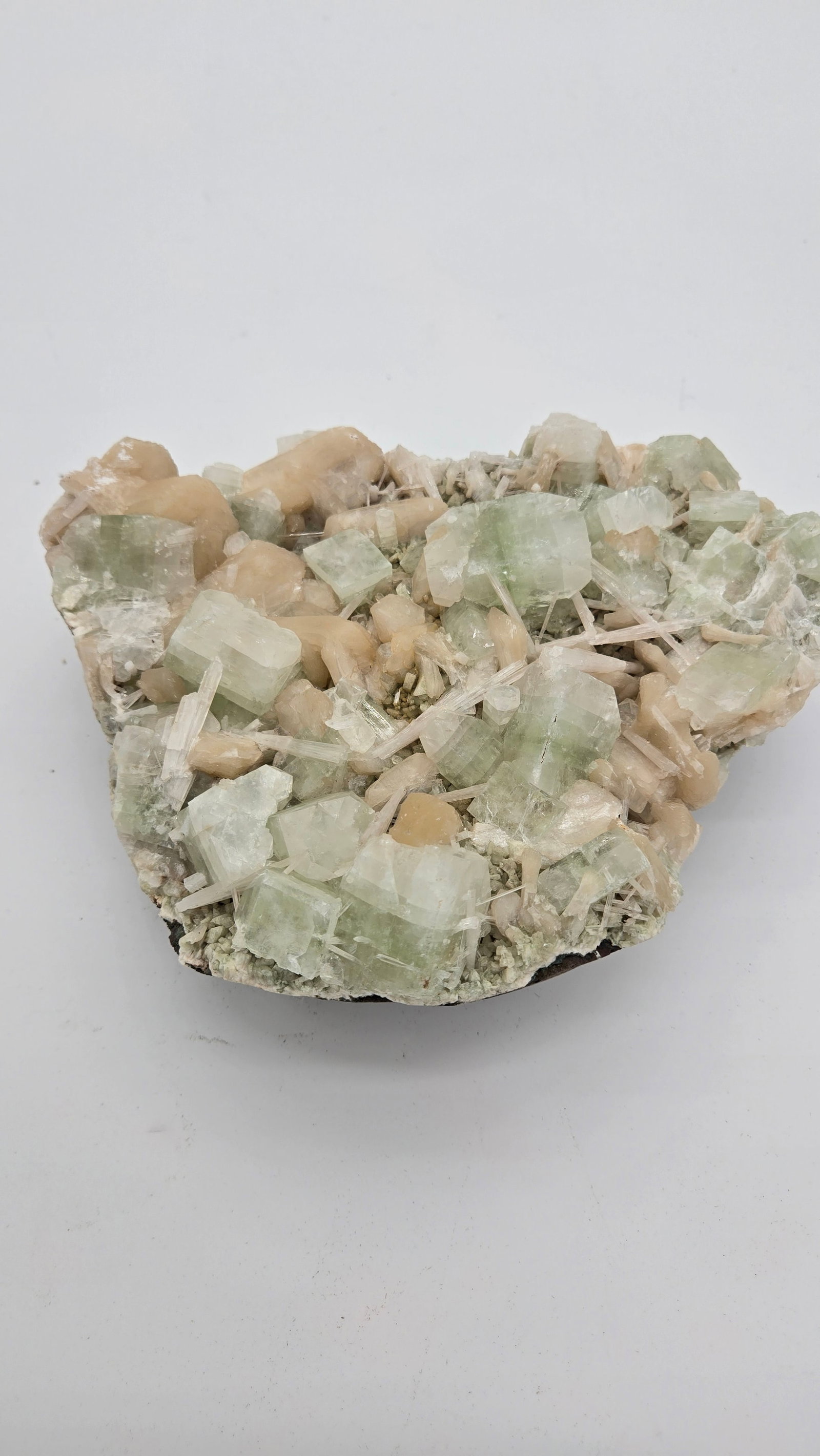 AN APOPHYLLITE SPECIMEN: Green and peach coloring. 9" wide