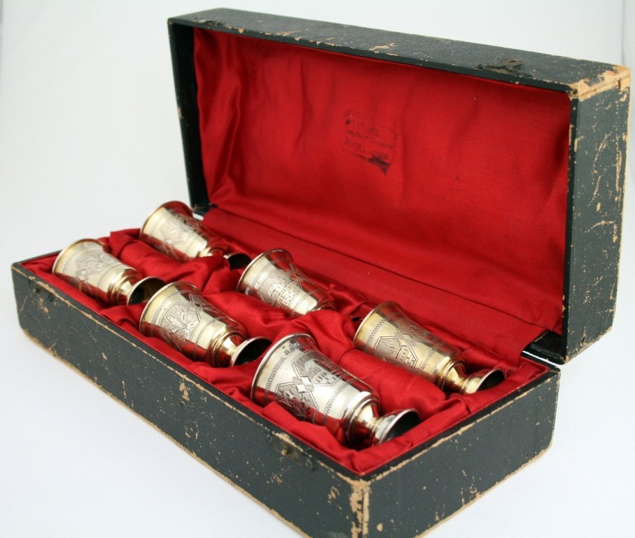 A SET OF SIX PARCEL GILT KIDDUSH BEAKERS IN ORIGINAL: A SET OF SIX PARCEL GILT KIDDUSH BEAKERS IN ORIGINAL BOX. Moscow, 1887. Engraved with town scenes. Marked. Each cup 2.7" tall. Estimate $600 - 900