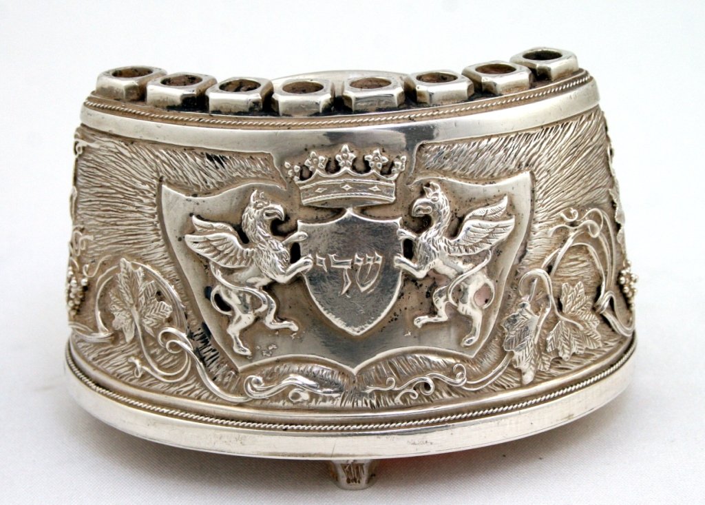 A SMALL MENORAH BY HENRYK WINOGRAD. New York, 1997.: A SMALL MENORAH BY HENRYK WINOGRAD. New York, 1997. Decorated with two winged griffons and G-d's name in a shield cartouche. Signed. 3.5" wide. Estimate $300 - 500