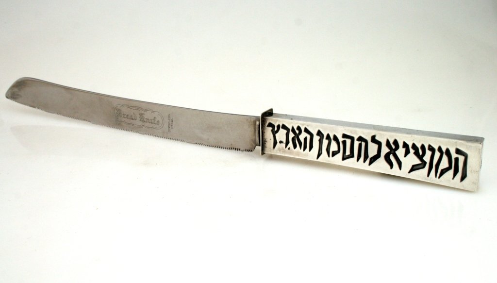 A SILVER HANDLED CHALLAH KNIFE BY BEZALEL. Jerusalem,: A SILVER HANDLED CHALLAH KNIFE BY BEZALEL. Jerusalem, 1950's. With imprint of the prayer over bread. 12.4" tall. Estimate $100 - 200