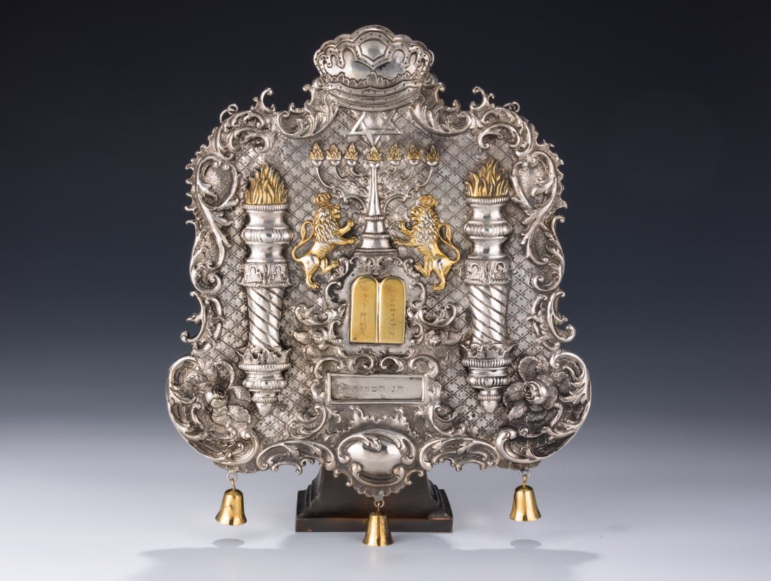 A LARGE SILVER TORAH SHIELD. Probably Romanian, c.: A LARGE SILVER TORAH SHIELD. Probably Romanian, c. 1880. Hand chased. Decorated with gilded lions, Solomonic pillars, a Mogen David and C-scroll designs. Marked. $16,500 – 18,500
