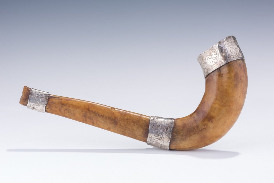 AN ANTIQUE SILVER MOUNTED SHOFAR. Continental, c. 1880.: AN ANTIQUE SILVER MOUNTED SHOFAR. Continental, c. 1880. Traditional in shape. With three sections of applied silver. Engraved in Hebrew with Yom Kippur related epithets. 11â€ long.