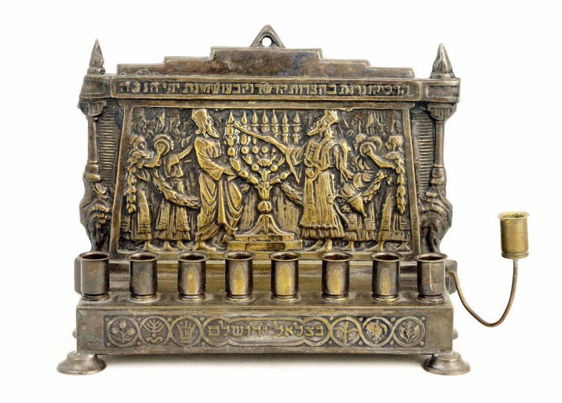 A BEZALEL CHANUKAH LAMP. Jerusalem, c. 1930. Embossed: A BEZALEL CHANUKAH LAMP. Jerusalem, c. 1930. Embossed with the high priest lighting the Temple lamp. 5.5Ó tall.