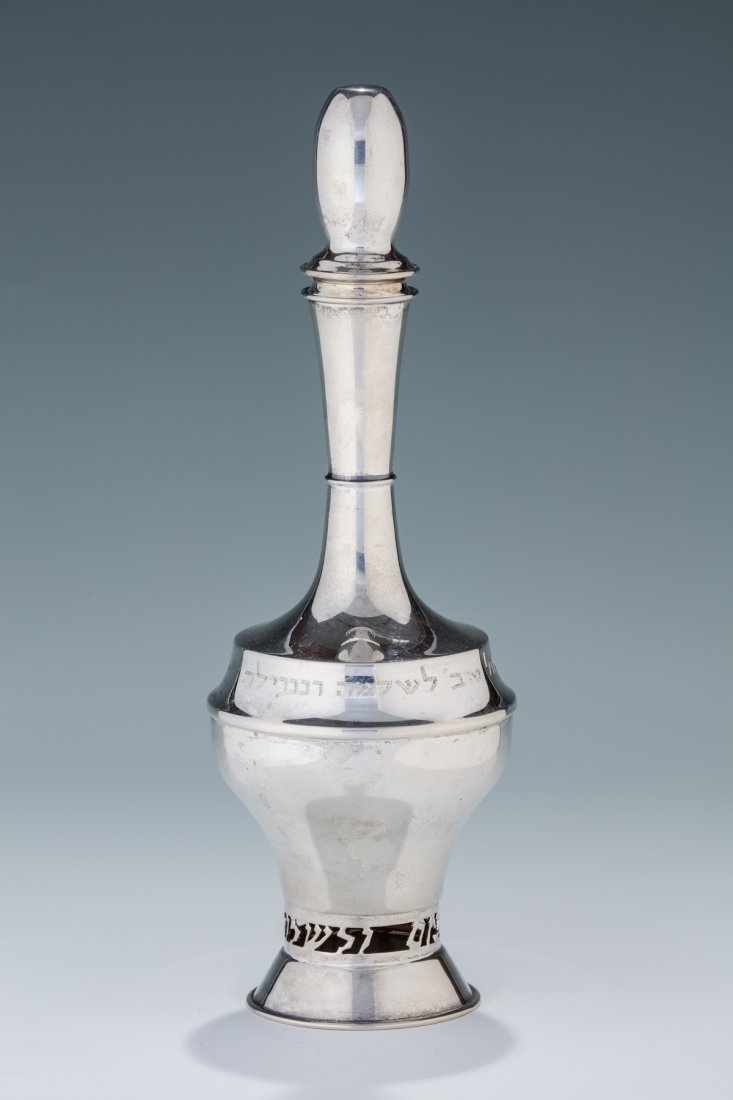 A STERLING SILVER WINE BOTTLE BY ART STERLING. Mexico,: Cut into base in Hebrew “TO A GOOD LIFE AND PEACE”. Also engraved with dedication in Hebrew “Mazel Tov to Shlomo and Neila from Baila Shpitzer” . 9.7” tall. Estimate $3,500 – 5,500