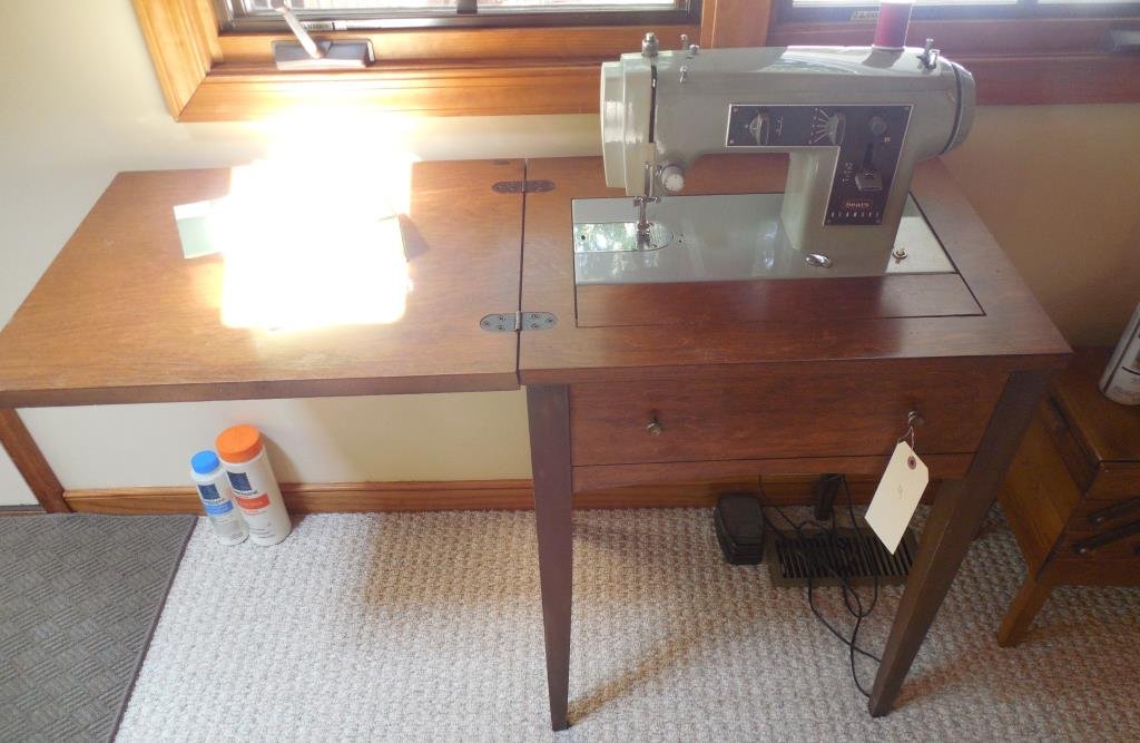 Kenmore Sewing Machine: Model 2142, Complete With Twenty-five Bobbins And Extra Needles, Button Hold Attachment, And Paperwork, Condensed Cabinet Size: 29 1/2" X 21" X 17 1/2". This Lot Is Locate Onsite And Will Be Available