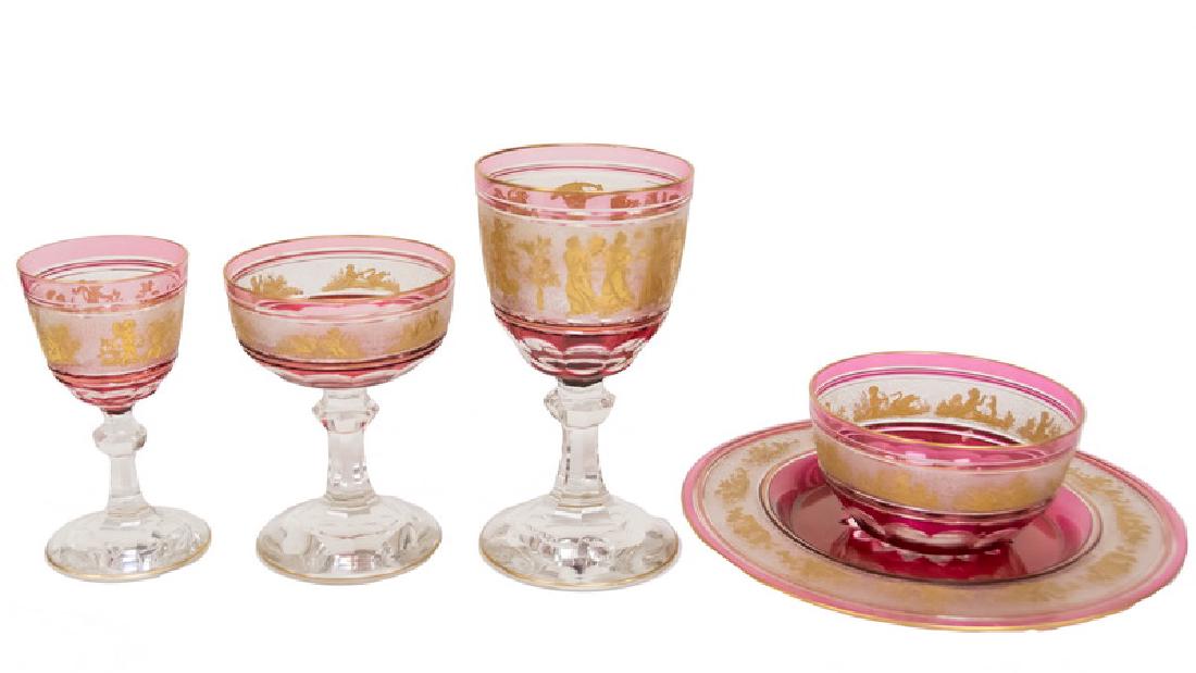 GILT RUBY & CLEAR GLASS TABLE SERVICE: comprising 8 water glasses (6 5/8"), 8 wine glasses (5 1/8"), 8 champagne coupes (5"), 7 finger bowls (4 1/2" diameter, 2 1/2" high), and 9 plates (8 1/2" diameter) [40 total pieces] Provenance: The E