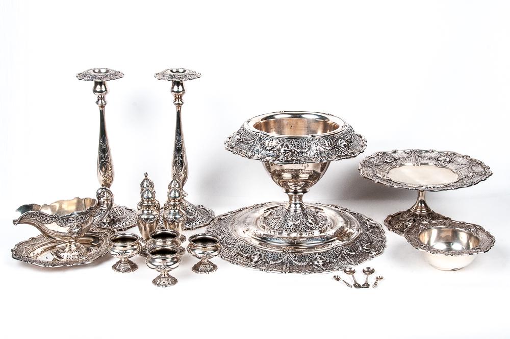 SIXTEEN-PIECE STERLING TABLE SERVICE: comprising a centerpiece with underplate, sugar bowl, dessert stand, gravy boat and underplate. pair of candlesticks, four salt cellars and four casters 212 total troy ounces the underplate: 16 inches