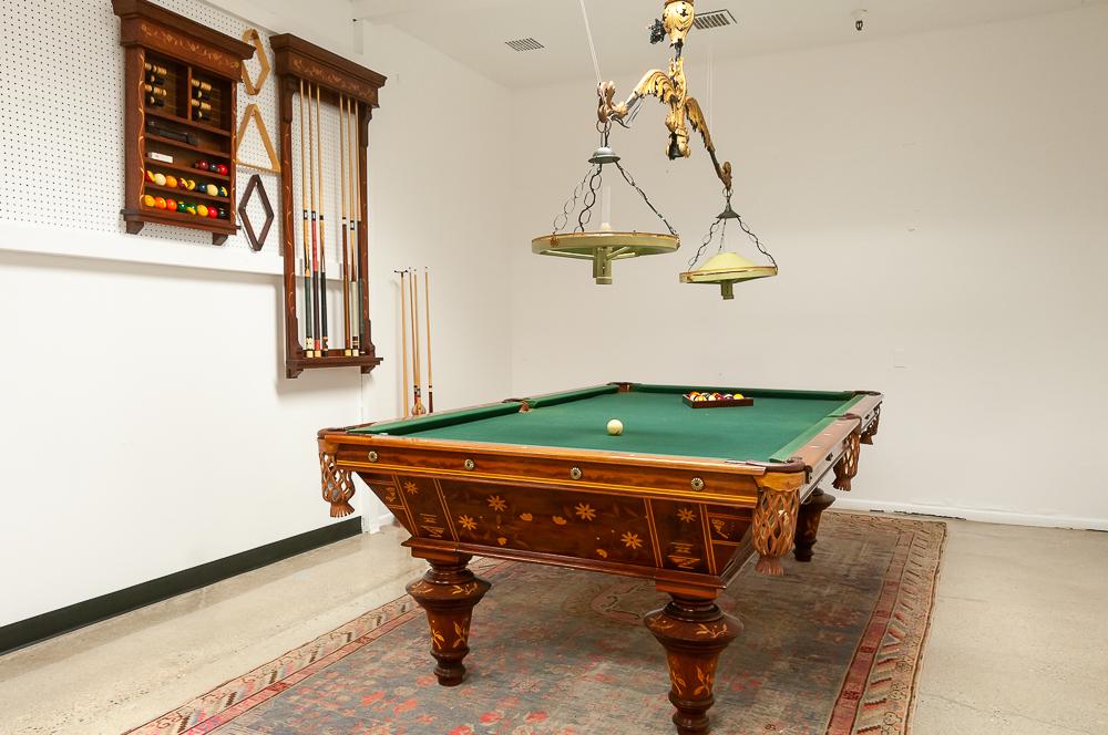 CARVED FRUITWOOD & MARQUETRY INLAID MAHOGANY BILLIARD: comprising a double-light pool fixture, 35 billiard balls, 9 pool cues, pool cue bridge, brush, pool cue stand, cue shelf, ball rack with score keeper, two triangle and two diamond racks 110 inches wi