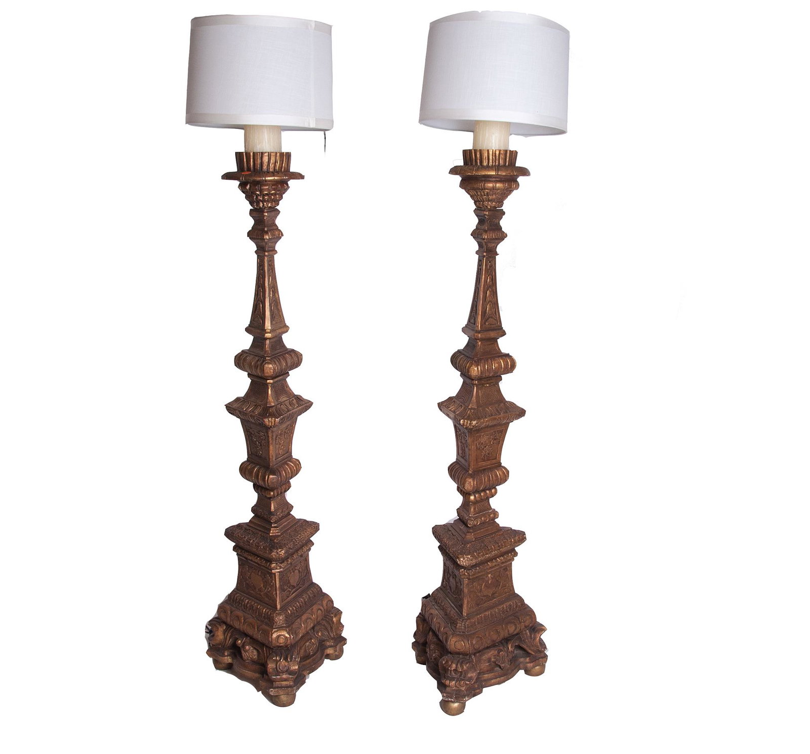 PAIR OF ITALIAN BAROQUE STYLE GILT TORCHERES: each electrified as a floor lamp; with contemporary circular shades Condition: good. Minor surface wear. Wiring should be checked by an electrician. Shades unlined and with lifting to ribbon trim. the