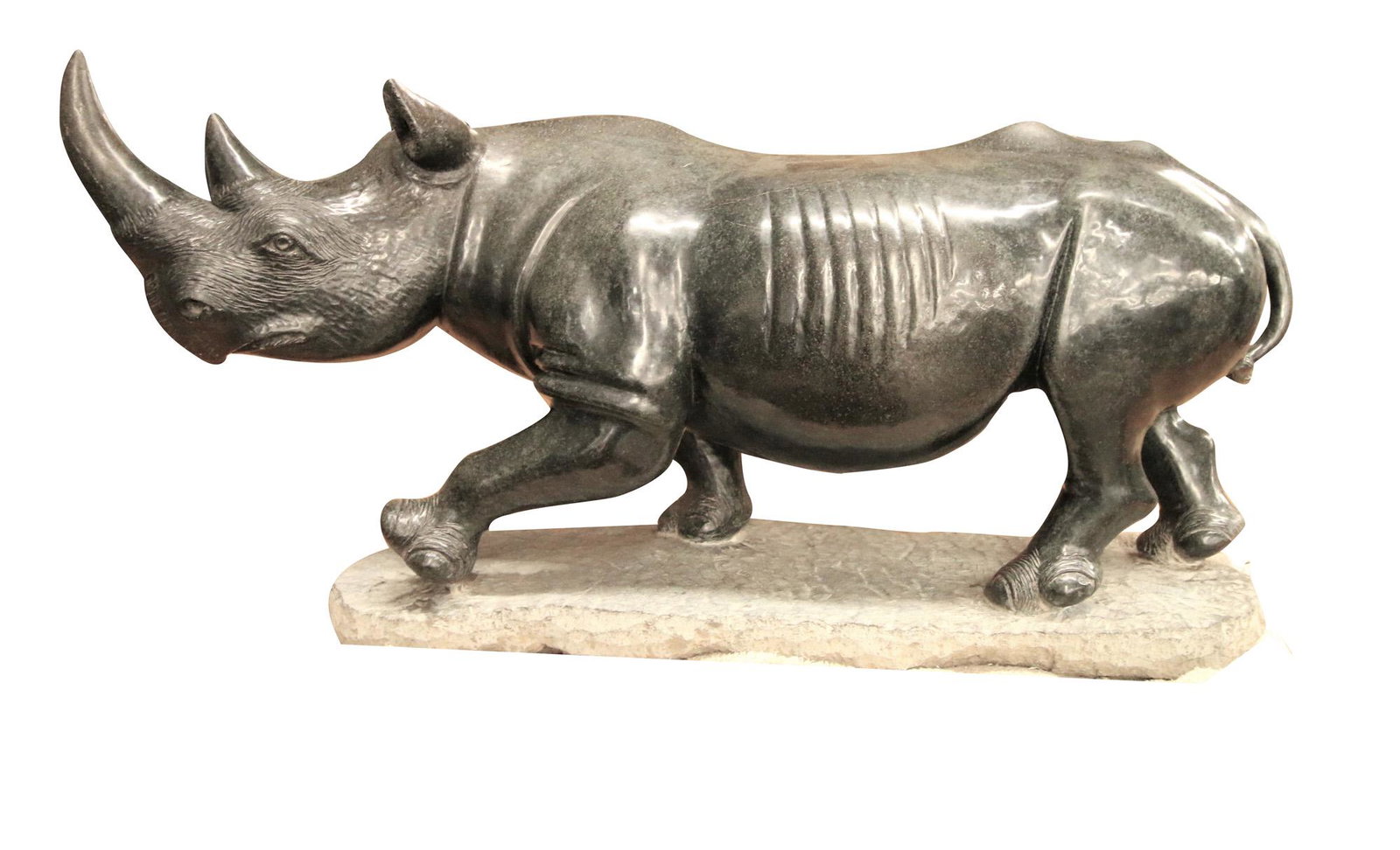CARVED SHONA STONE RHINOCEROS: on a stone plinth Condition: with surface scratches and nicks throughout 33 inches wide; 12 inches deep; 17 1/2 inches high