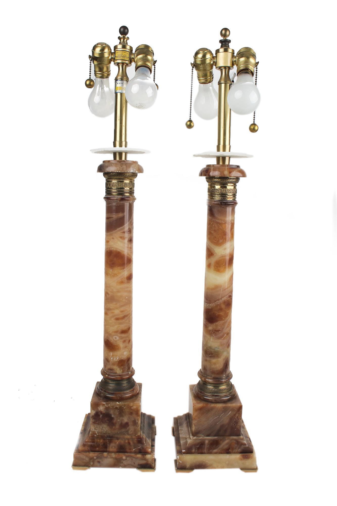 PAIR OF GILT METAL-MOUNTED ONYX TABLE LAMPS: each with columnar standard with acanthus-cast collar, on a square plinth Condition: with a few minor nicks to alabaster corners and edges. No shades. Wiring should be checked prior to use. each 24 in