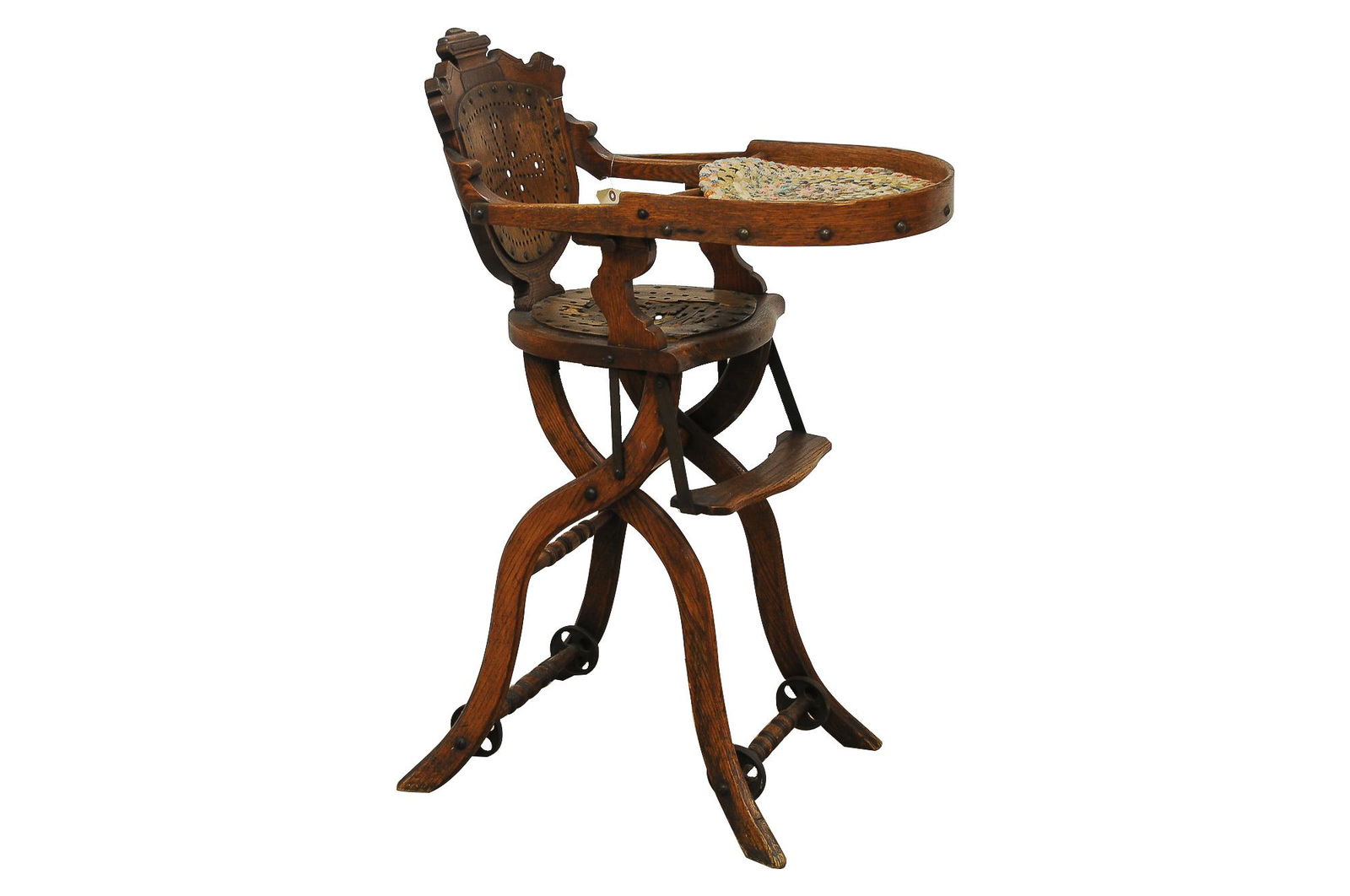 VICTORIAN CARVED HIGH CHAIR: oak with iron mounts and wheels, the back and seat with pierced designs Condition: seat with wear and in need of repair; the tray nicked and split; the arm support with separation and loss 37 total in