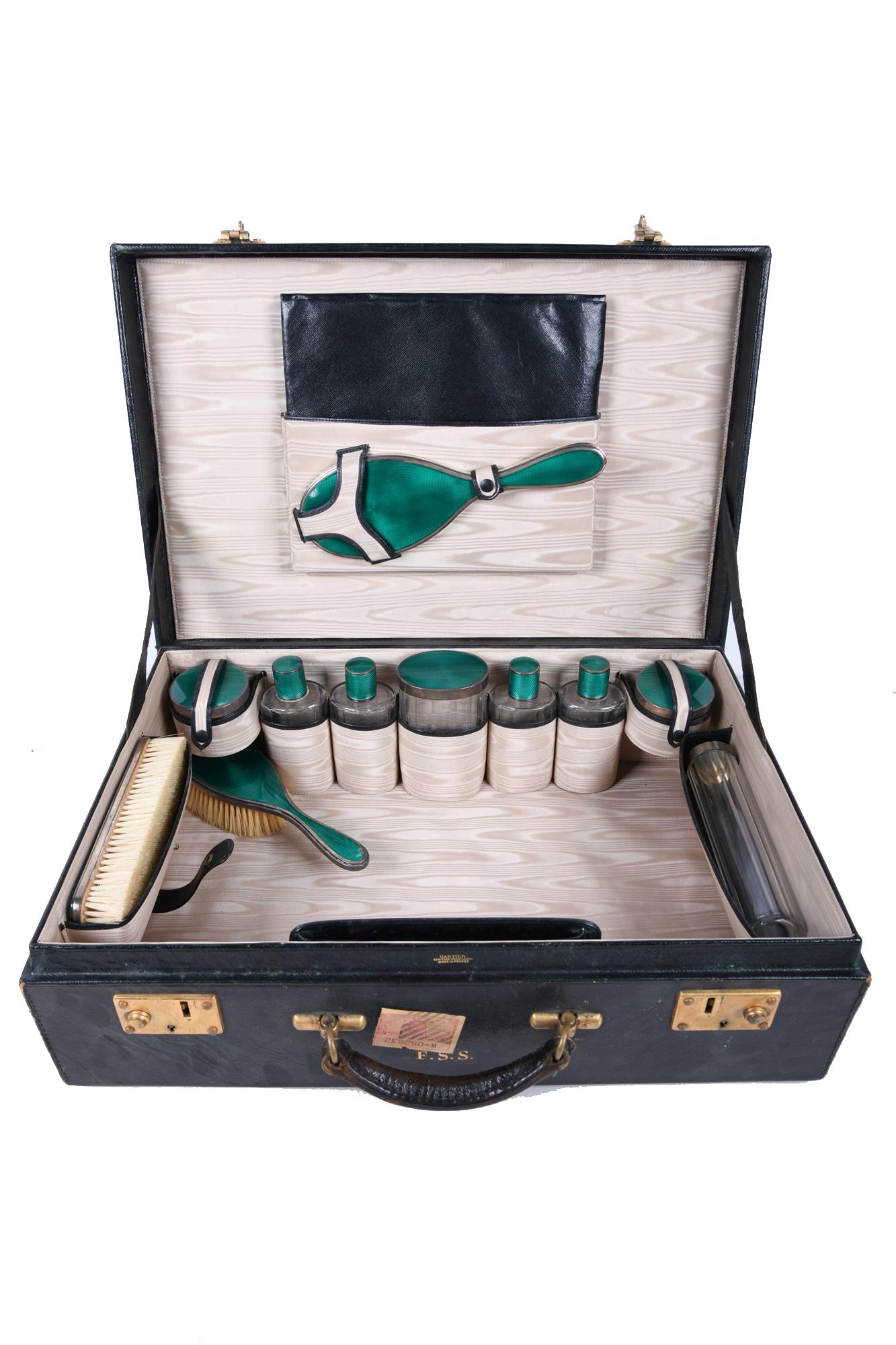 CARTIER FRENCH SILVER & GREEN ENAMEL TRAVELING TOILET: 12 total pieces with French silver hallmarks case signed Cartier case, brush and hand mirror with monogram: F.S.S. Condition: with loss to enamel on long handle brush, mirror and several jars; chips t
