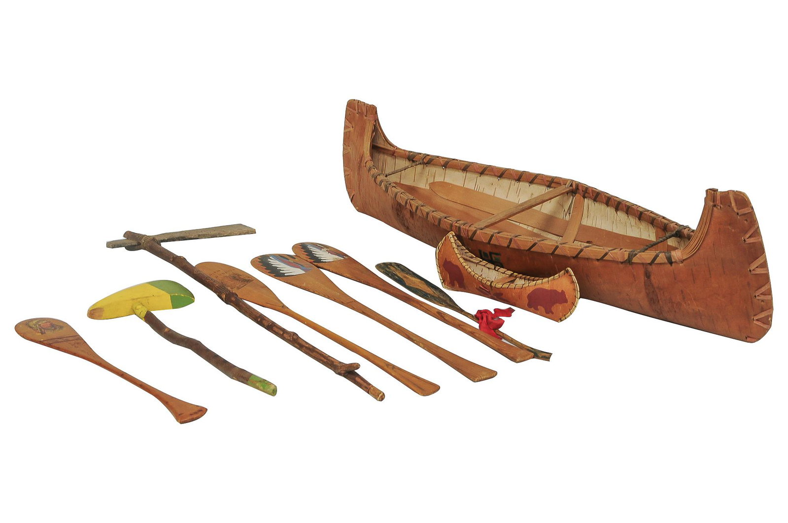 DECORATIVE MODEL OF CANOE WITH IMPLEMENTS: circa 1920's to late 20th Century wood, paper and mixed media including: a large canoe, a small canoe, five oars and two hatchets with various inscriptions throughout Condition: damage to large canoe 