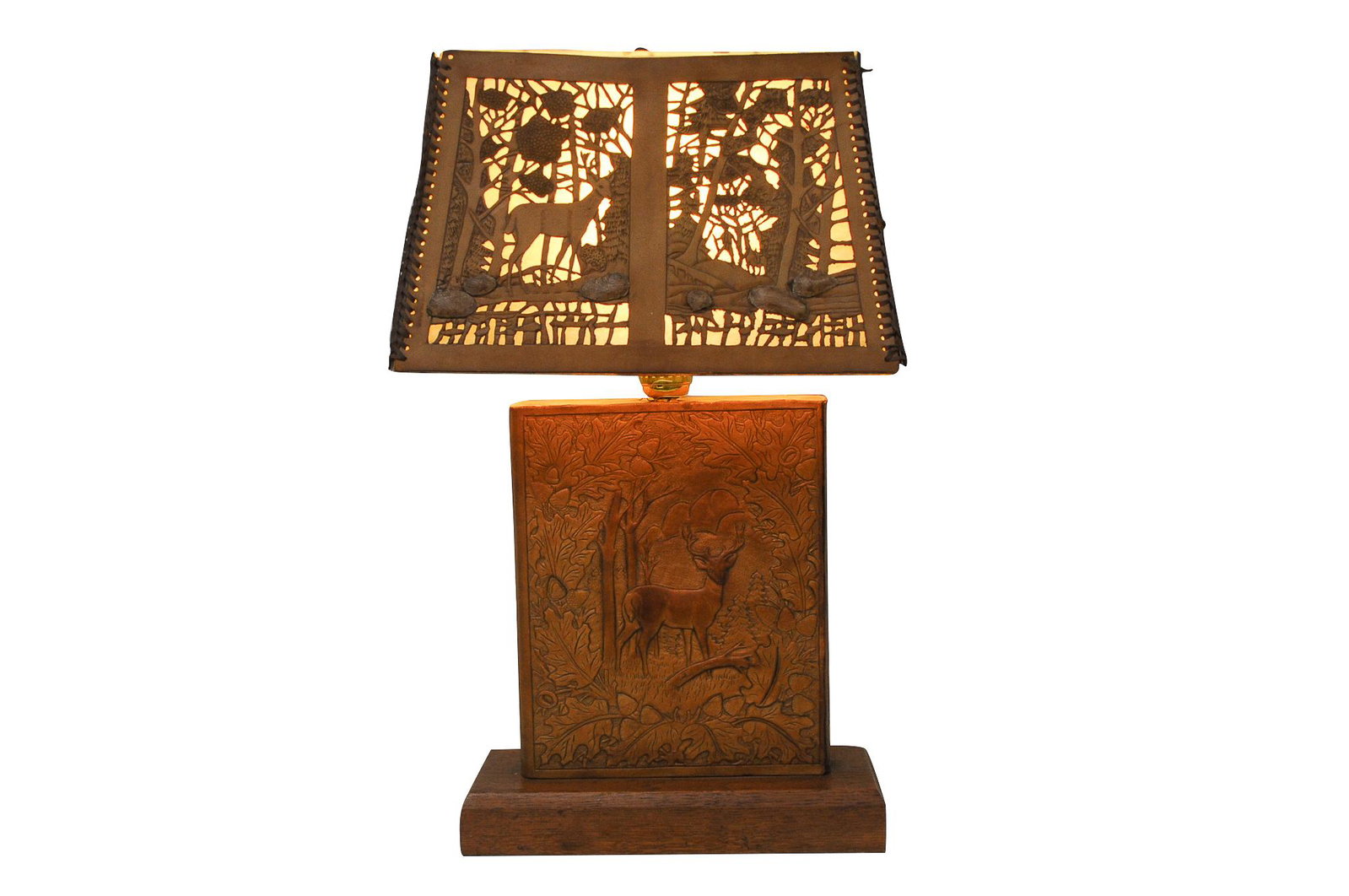 LEATHER STAG MOTIF TABLE LAMP: circa 20th Century leather, hide and wood tooled leather base and shade depicting stags on all sides Condition: with loss to leather binding on shade and consistent wear and separation of leather 22 t