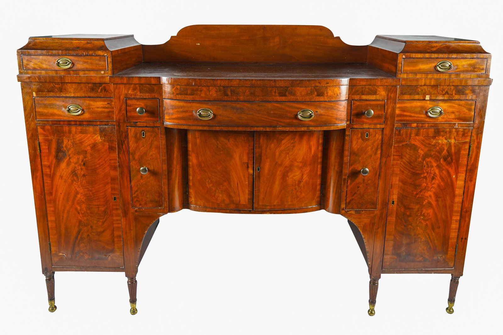 AMERICAN MAHOGANY-VENEER BUFFET: early 2late 19th / early 20th century, with an arrangement of fitted drawers, cupboards, and slide-out surfaces, on brass-clad feet Condition: with wear commensurate with age and scattered small losse