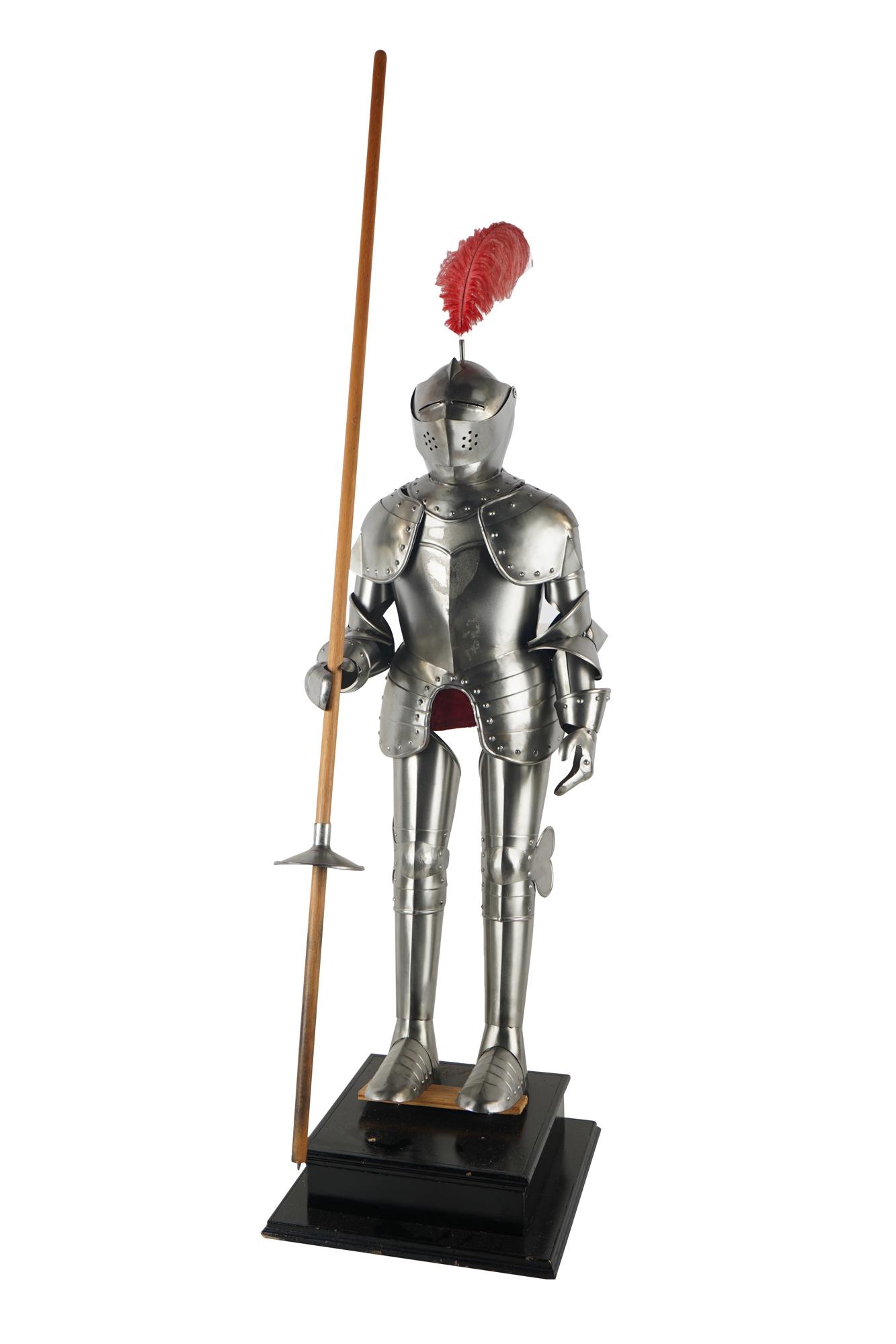 DECORATIVE DIMINUTIVE SUIT OF ARMOR: resting on a wood base, holding a wood staff Provenance: The Estate of Barron Hilton the suit to top of helmet: 38 inches high; 50 1/2 total inches high