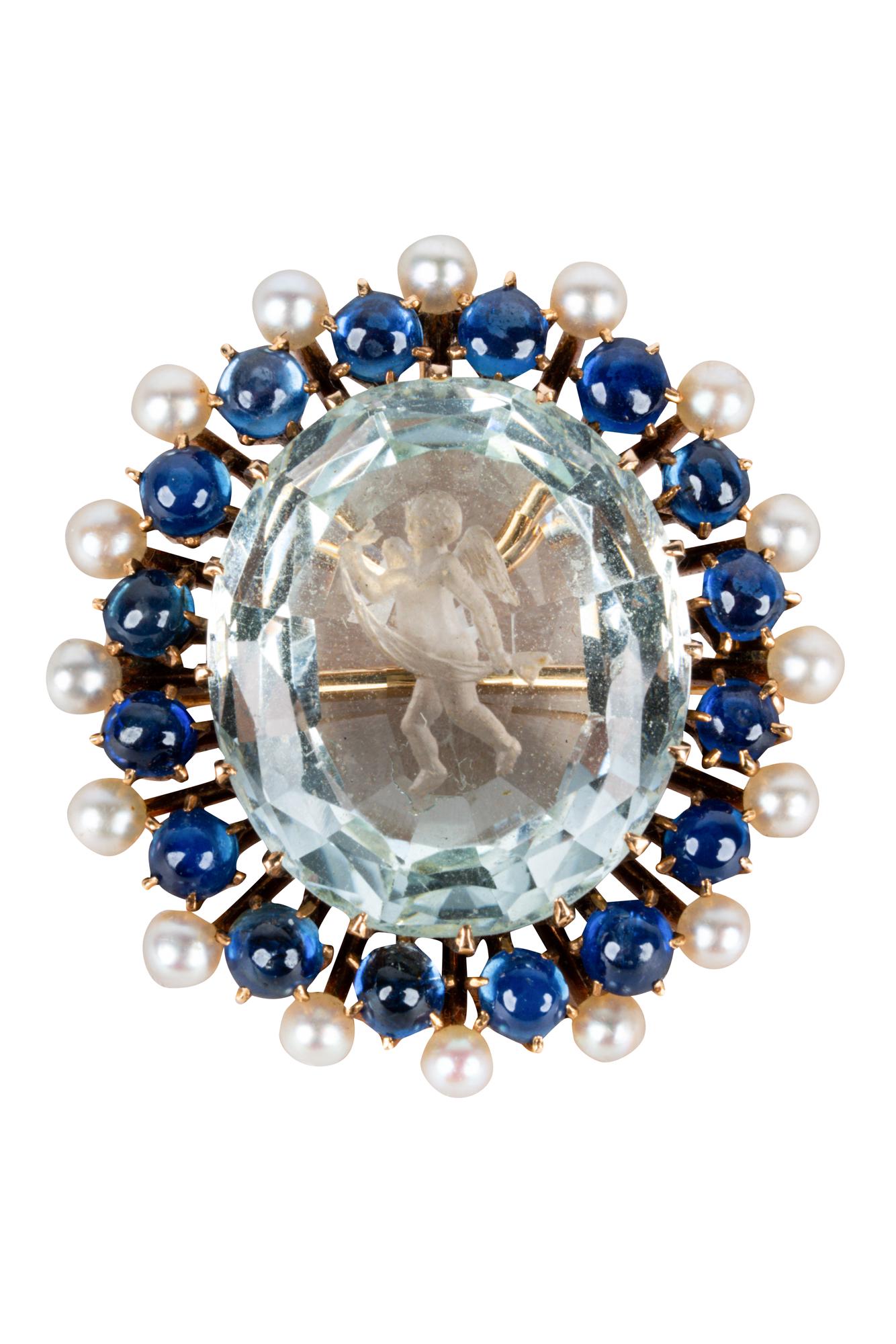 14 KARAT YELLOW GOLD, SAPPHIRE, SEED PEARL, & CARVED: centering one carved aquamarine intaglio with a cherub motif weighing approximately 13.0 carats; with a halo of cabochon cut sapphires and cultured seed pearls 11.3 grams 29.40 x 26.80 mm