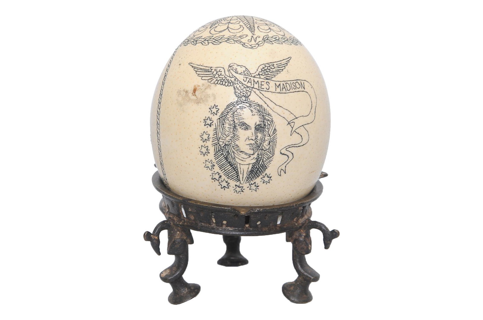 SCRIMSHAW OSTRICH EGG ON STAND: depicting a portrait of James Madison and clipper ships Provenance: The Estate of Penny Marshall egg: 5 1/2 inches high; stand: 3 inches high
