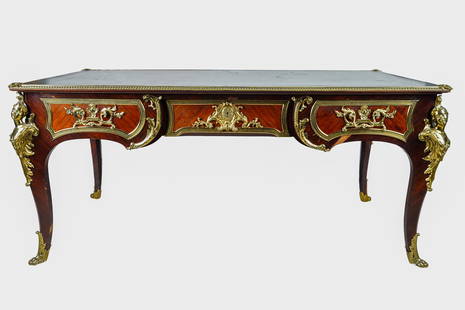 TREATY OF VERSAILLES ORMOLU-MOUNTED BUREAU PLAT: late 19th century, after a model by Charles Cressent with gilt-tooled green leather-inset top over three drawers, on cabriole legs each headed by an espagnolette; the frieze on left and right-hand