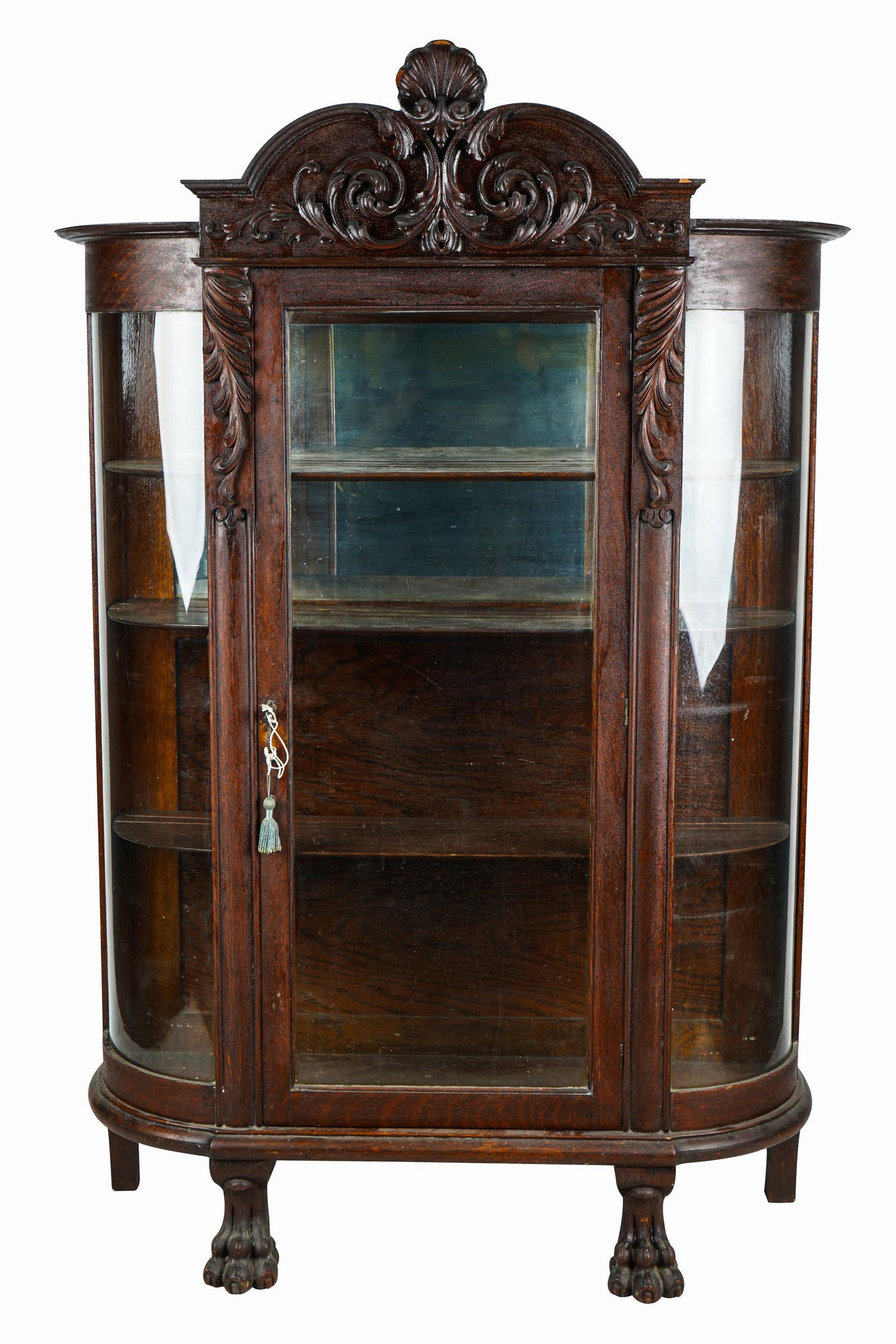AMERICAN CARVED OAK VITRINE CABINET: 19th century the glazed, hinged door and glazed, curved side panels enclosing three shelves, raised on paw feet; with key 44 inches wide; 15 inches deep; 71 1/2 inches high