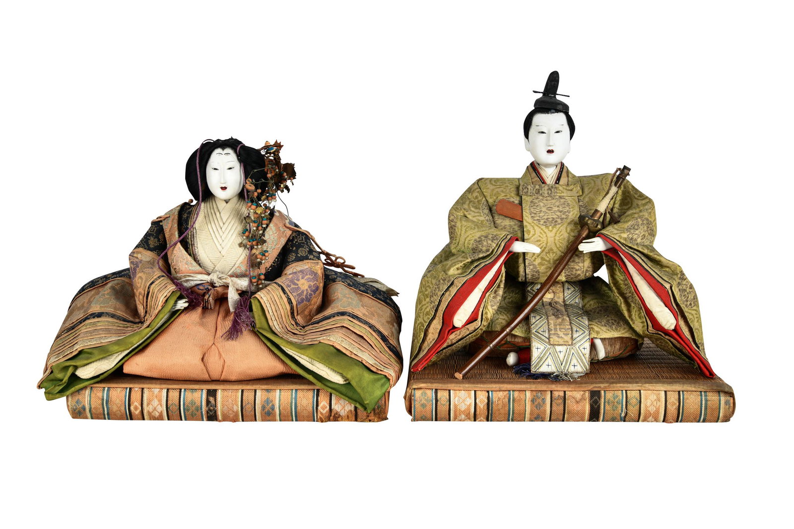 PAIR OF JAPANESE DOLLS: each with painted wood head and hands, sitting on a reed and fabric base each 11 1/2 inches wide; 8 inches deep; the taller: 12 1/2 inches high