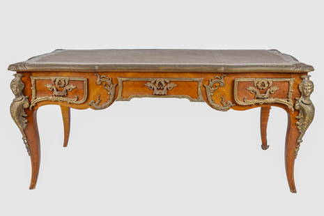 TREATY OF VERSAILLES LOUIS XV STYLE BUREAU PLAT: after the model by Charles Cressent, with brown gilt-stamped leather or vinyl-inset top over three drawers opposing three false drawers Condition: gilt bronze mounts in fair condition, darkened and wi