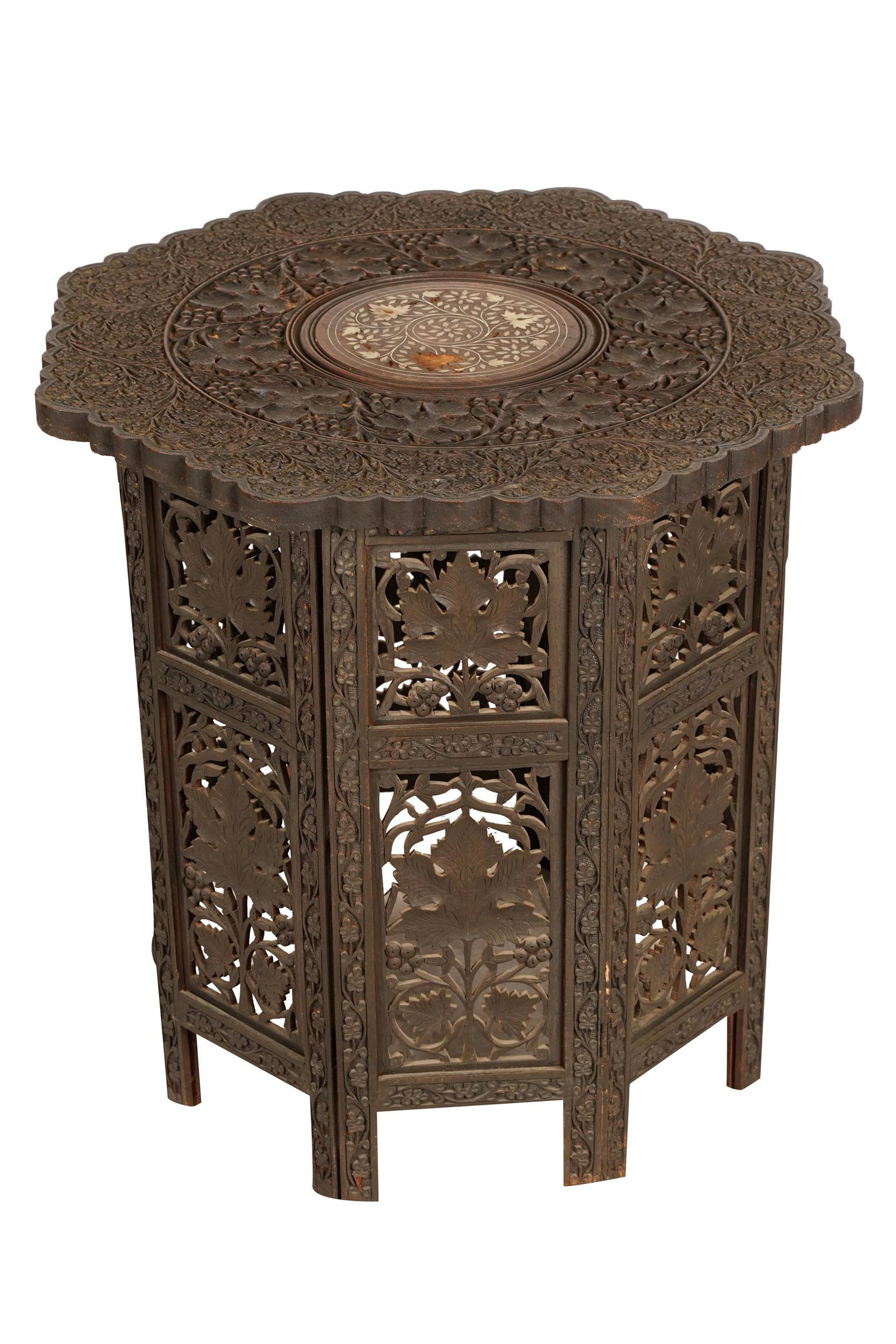 LEVANTINE STYLE CARVED WOOD FOLDING SIDE TABLE: octagonal, the relief-carved top with bone-inlaid central medallion; the sides with pierced panels Condition: areas of center inlay missing; also missing wood one side panel; chips at corners 22 1/4 i