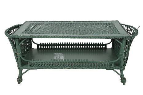 GREEN-PAINTED WICKER COFFEE TABLE: with undershelf and a pocket at each end Provenance: The Estate of Judith Krantz, Bel Air Condition: with losses and lifting to wicker. Part of a label stuck to undershelf 50 inches wide; 20 inches