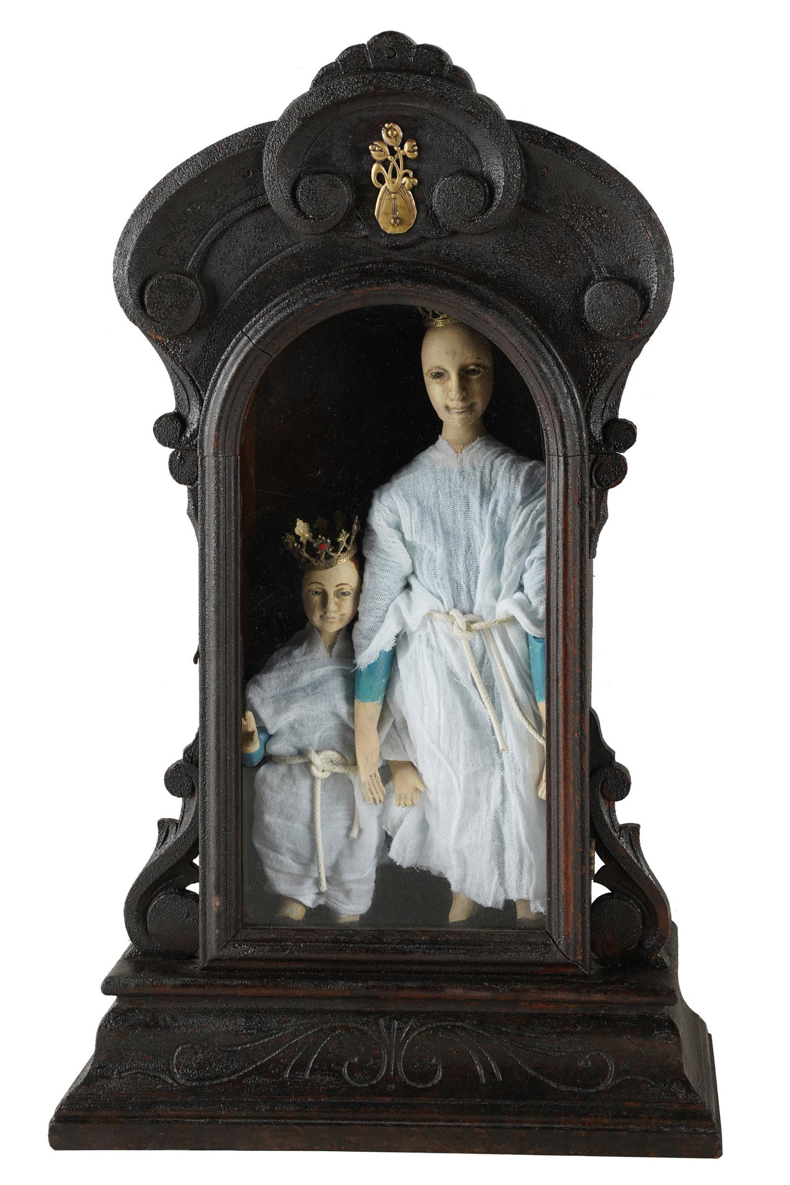 SPANISH COLONIAL-STYLE MADONNA & CHILD GROUP: the two dolls in traditional costume in a wood wall cabinet; Condition: with alligatoring to finish of cabinet; 20 1/2 x 12 inches