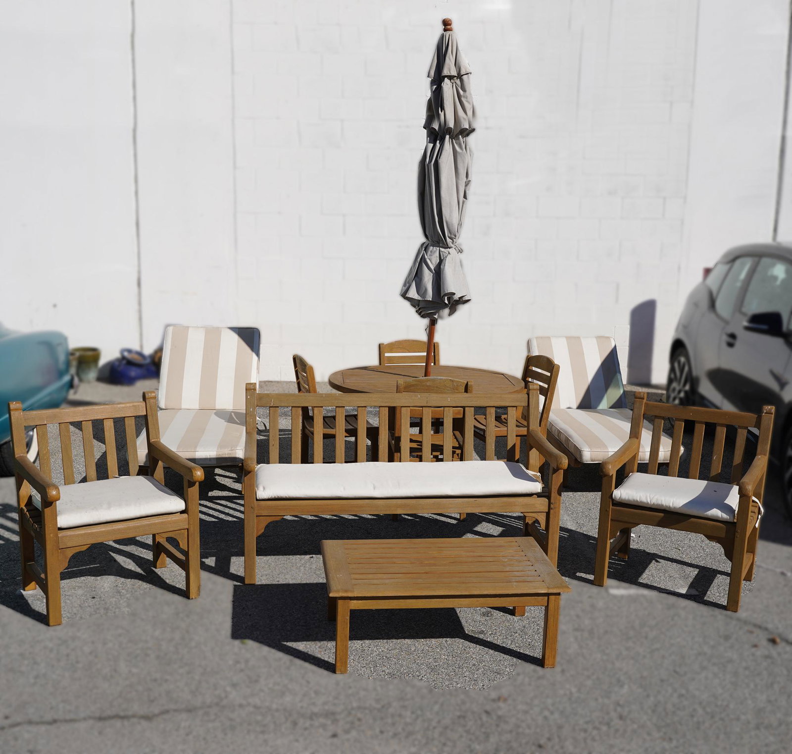 NORMAN LEAR: SET OF TEAK PATIO FURNITURE: comprising a table (47 1/2 in. diameter; 28 in. high), an umbrella (fits into base of table), four side chairs (17 in. wide; 18 in. deep; 33 1/2 in. high; seat height: 17 1/2 in.), two chaises (26 in.