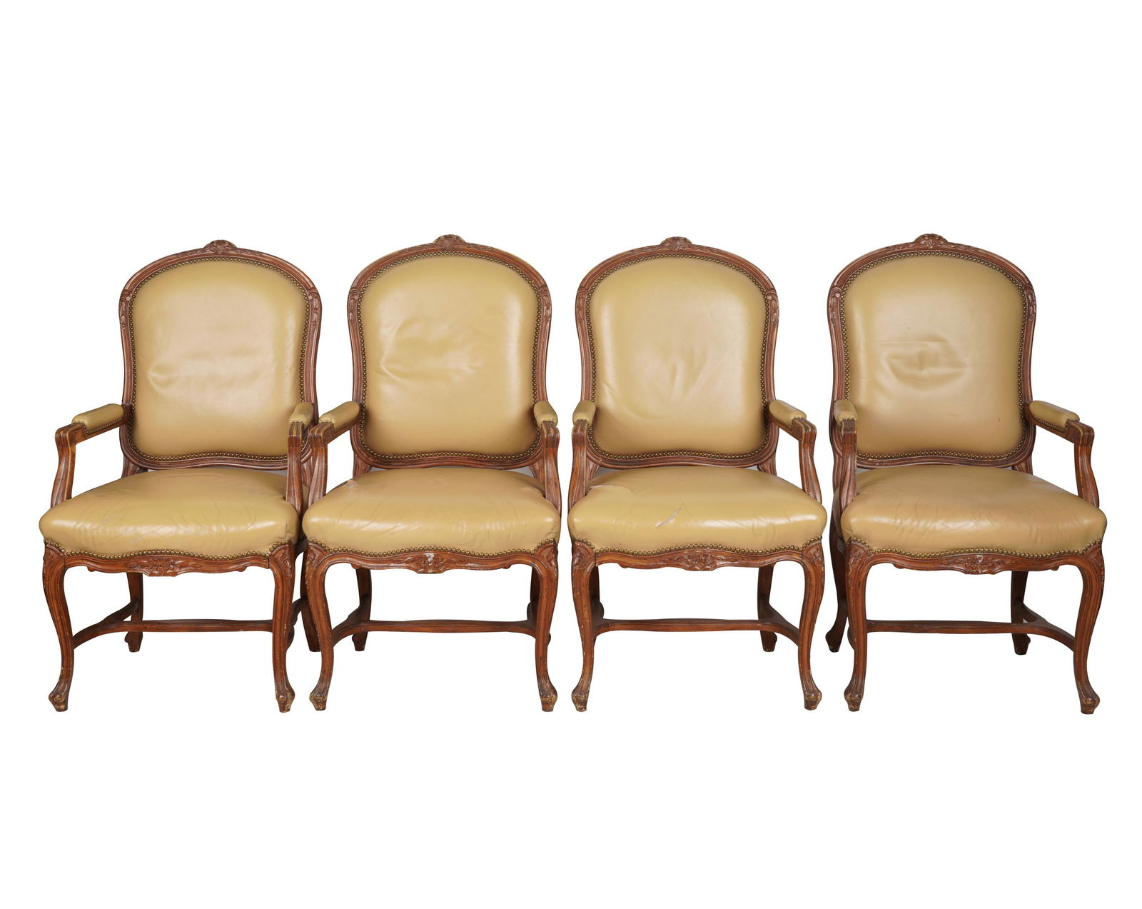 SET OF FOUR ROCOCO-STYLE CARVED WOOD ARMCHAIRS: after 1950; covered with tan leather; Provenance: Chuck Fries, Godfather of the Television Movie, and Ava Fries Estate, Beverly Hills; Condition: nicks and wear to finish; tears to leather on seats; 2