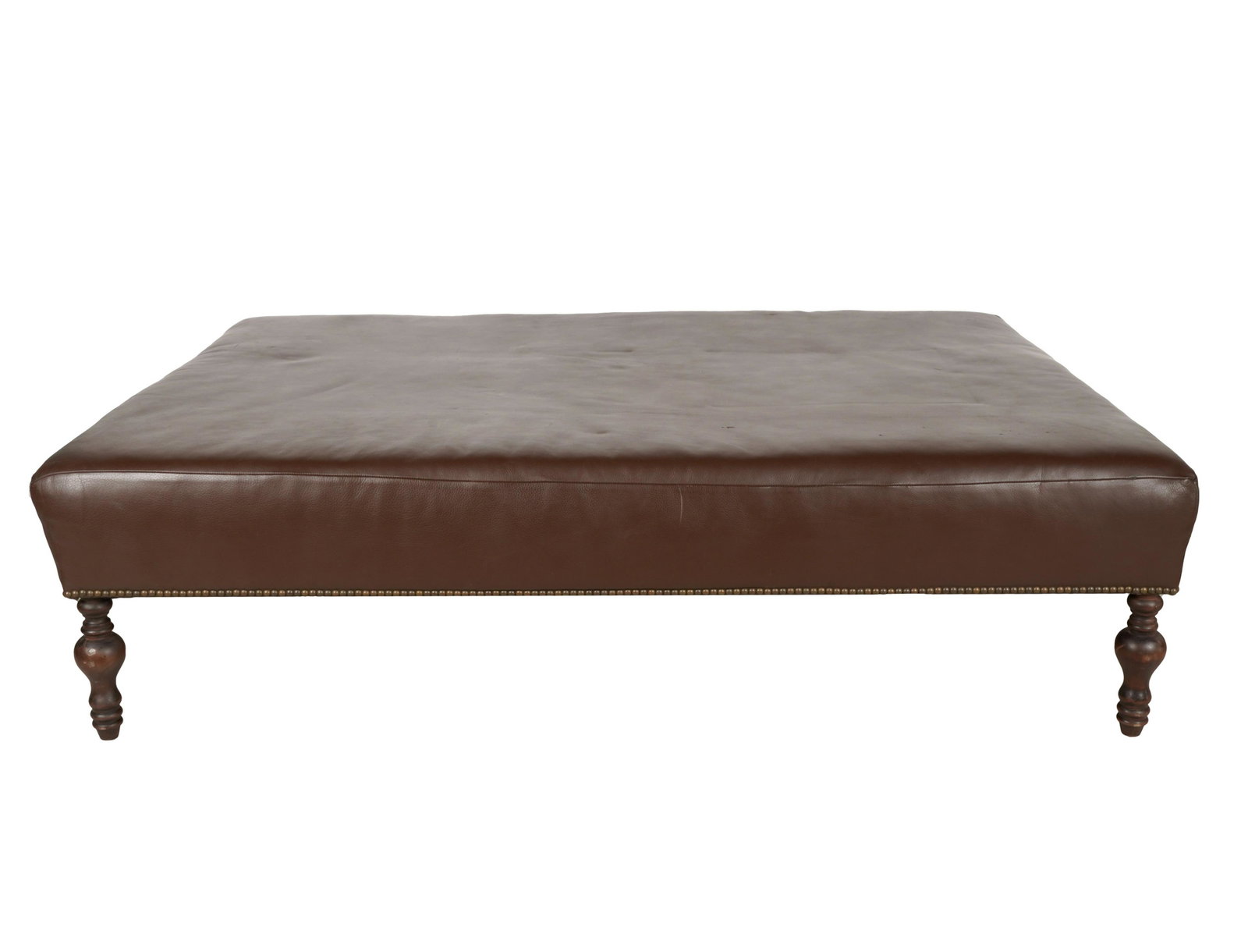 BROWN LEATHER OTTOMAN: manufacturer unknownl; on wooden legs; Provenance: The Jim Belushi Collection, a Michael Smith Installation; 66 inches wide; 48 inches deep; 18 inches high
