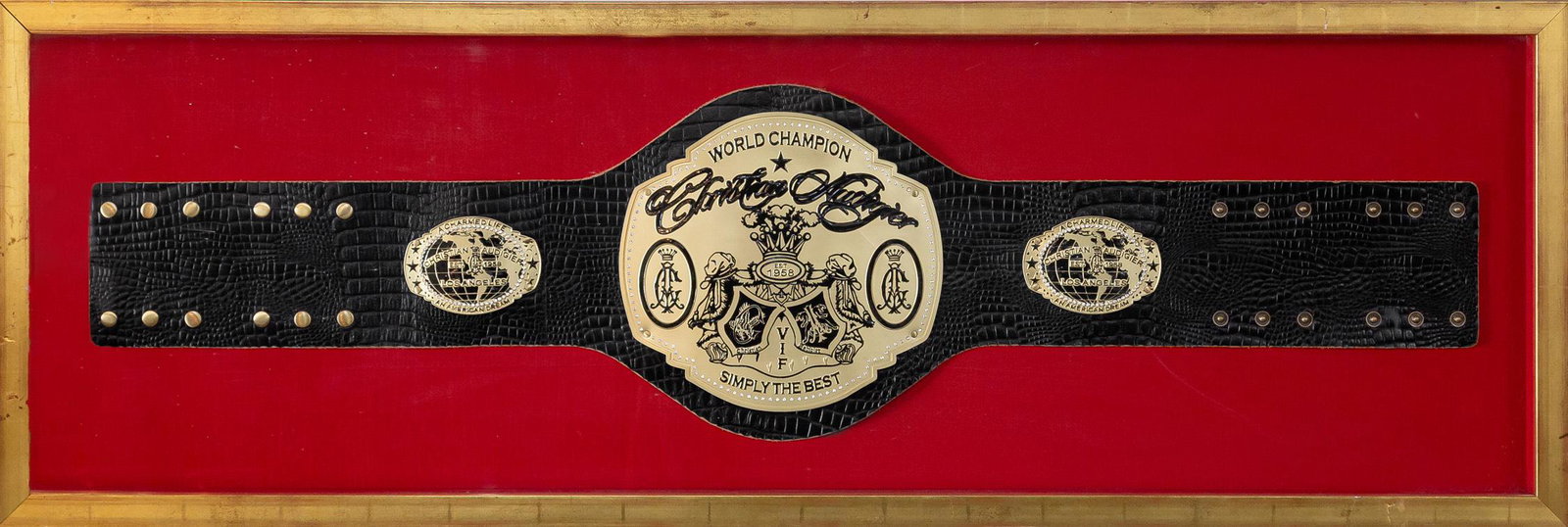 CHRISTIAN AUDIGIER "WORLD CHAMPION VIF" FRAMED BELT: The center of the professional boxing / wrestling style championship belt with a coat of arms flanked on either side by Audigier's stylized crowned 'CA' monogram and surmounted by his name in script, 
