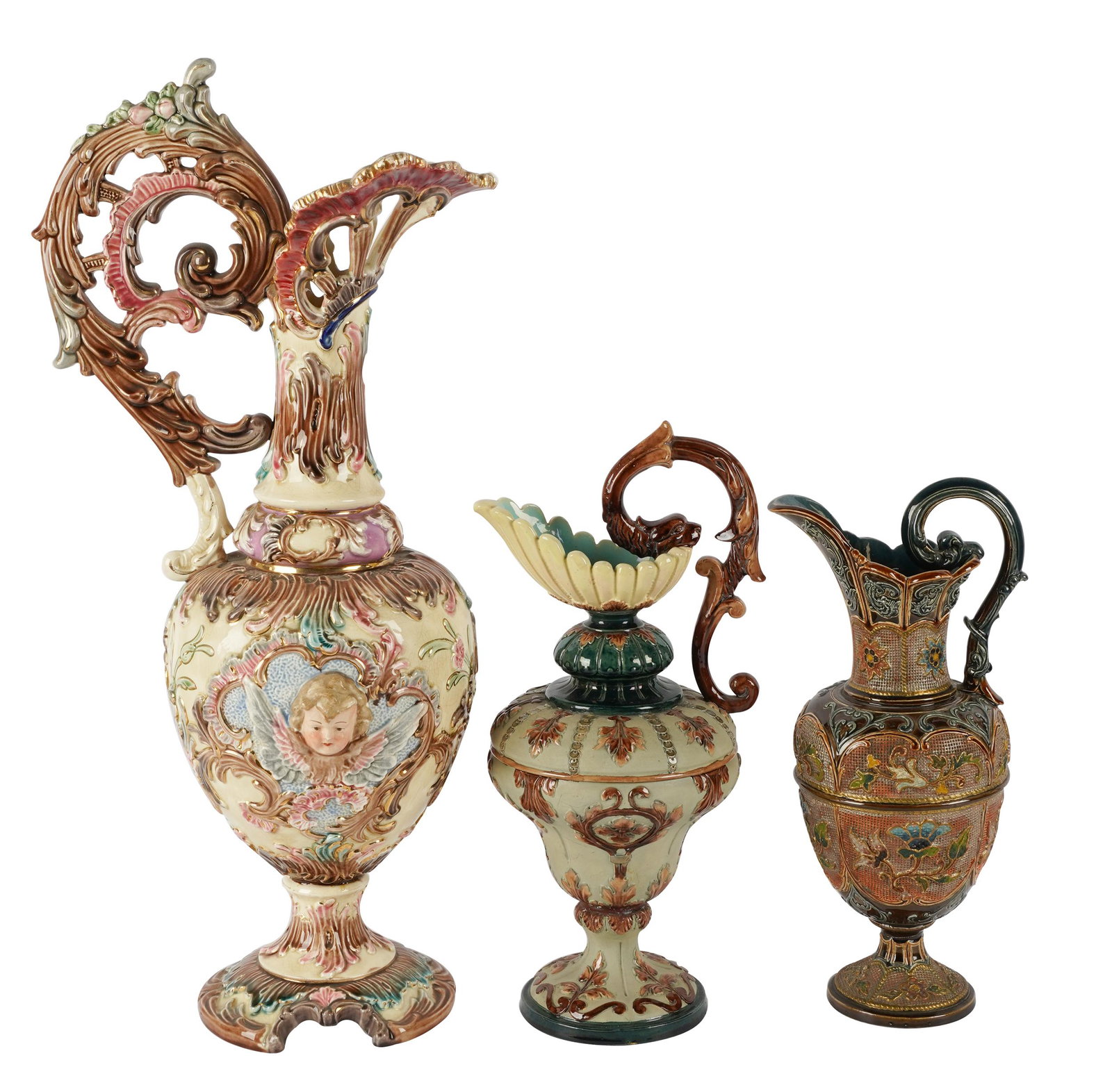 THREE MAJOLICA EWERS: the first: impressed mark "Eichwald" (22 inches high); the second: molded mark "WS[ampersand]S", with matte green ground (14 inches high); the third: raised oval molded mark "GR" (?), with dark brown 