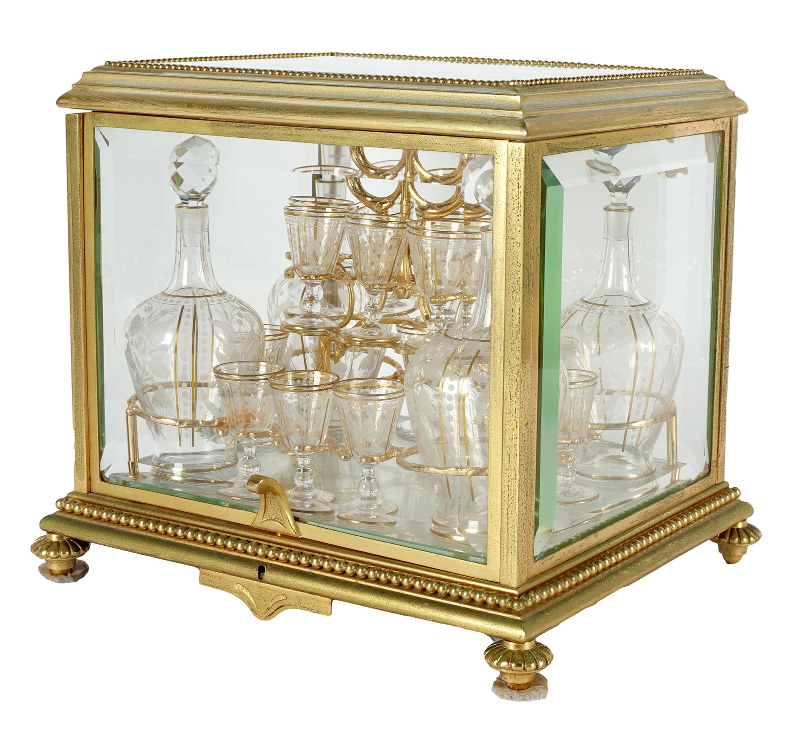 GILT METAL & GLASS TANTALUS: the box with beveled glass panels, the hinged top and front opening to a removable rack on a glass base fitted with four decanters ( 8 1/4 inches high) and sixteen cordial glasses (2 3/4 inches high),