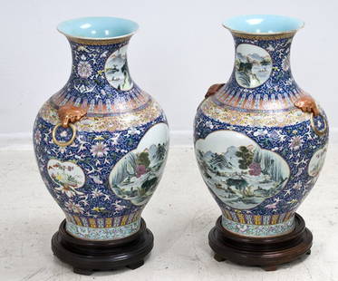 PAIR OF CHINESE POLYCHROME PORCELAIN VASES: each with a central reserve of a landscape and an enameled body with a foliate design; on a wood base 25 1/2 inches high