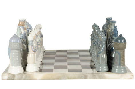 Lladro Porcelain Chess Set: designed by Juan Ignacio Aliena, 1996; each piece with factory mark; with an associated stone board; unsigned, 18 x 18 in. (45.7 x 45.7 cm.) Kings: 6 3/4 in. high