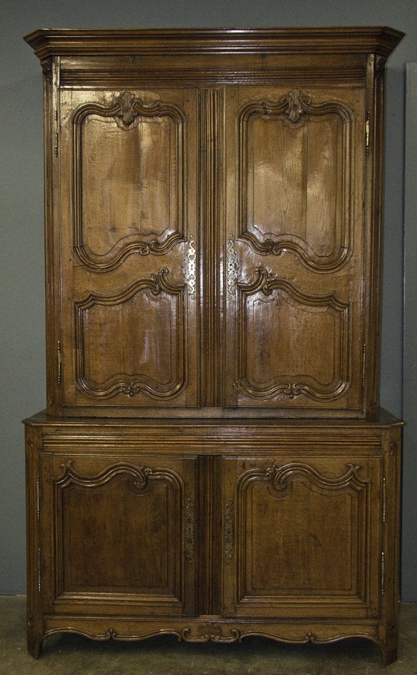 REGENCE PROVINCIAL CARVED OAK BUFFET A DEUX CORPS: the molded cornice above a pair of carved doors atop a two door cupboard 64 1/2 inches wide; 24 inches deep; 100 inches high