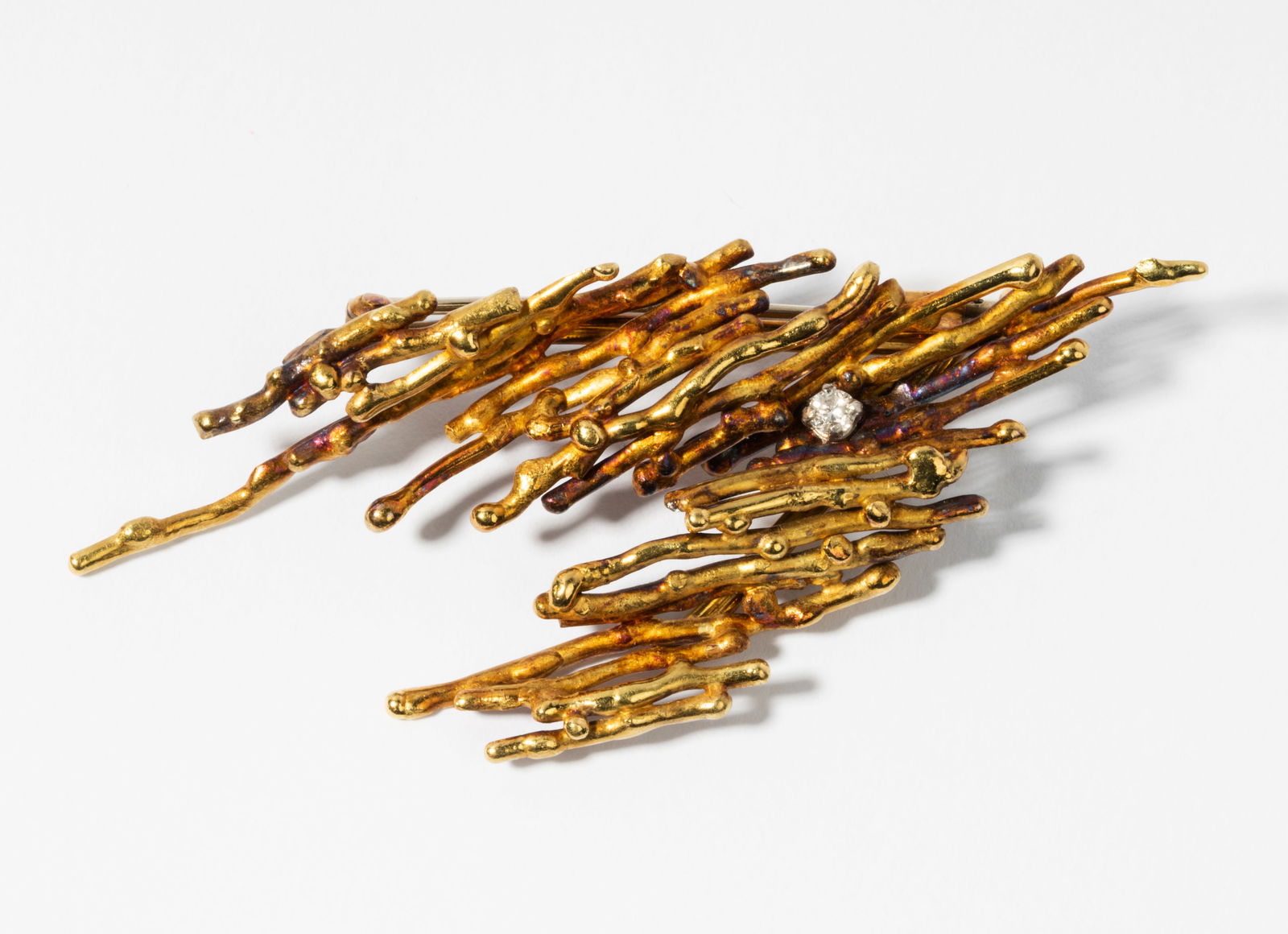 Andrew Grima 18 Karat Yellow Gold and Diamond Brooch: Circa 1970s, with British hallmarks, signed Grima; containing one full-cut diamond [G-H/VS] weighing approximately 0.10 carat total; completed with a pinstem and trombone catch; 71.60 x 31.25 mm; 16.5