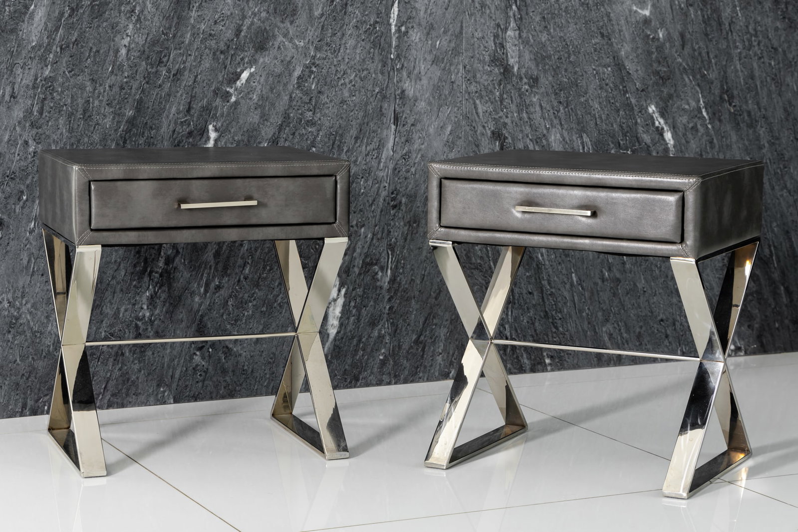 Pair of Polished Metal Upholstered Bedside Tables: faux leather upholstery over polyurethane foam padding, x-bases, no maker's label 24 x 22 x 17 in. (61 x 55.9 x 43.2 cm.) Provenance: Beverly Hills private residence